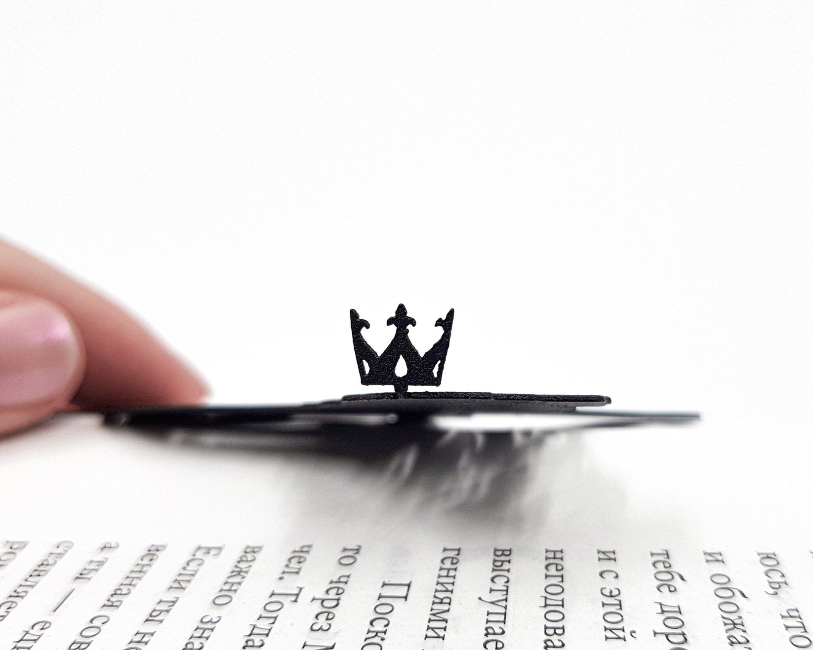 Lion, The King of Animals metal bookmark held in a hand above an open book