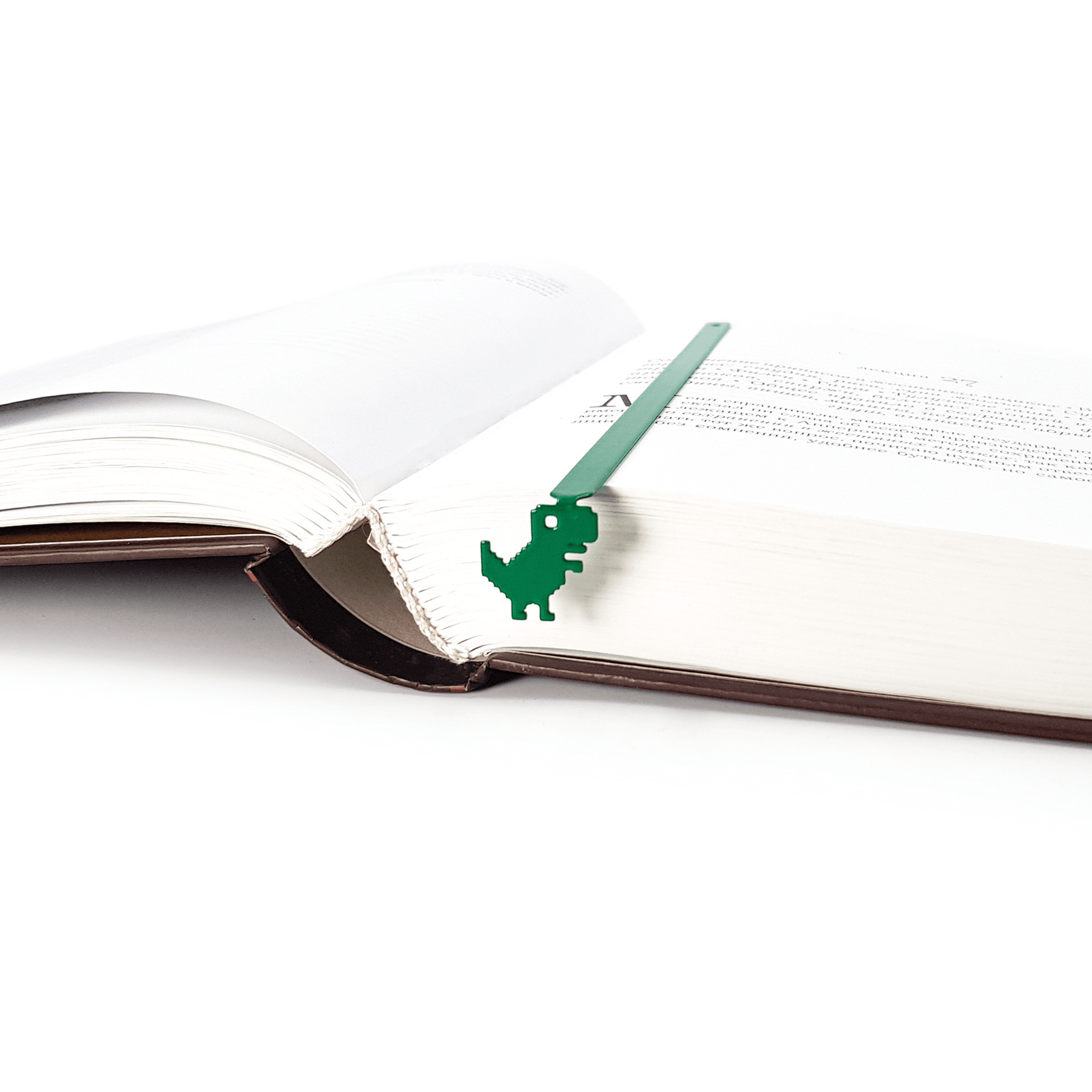 Little Dino metal bookmark in green resting on the pages of an open book