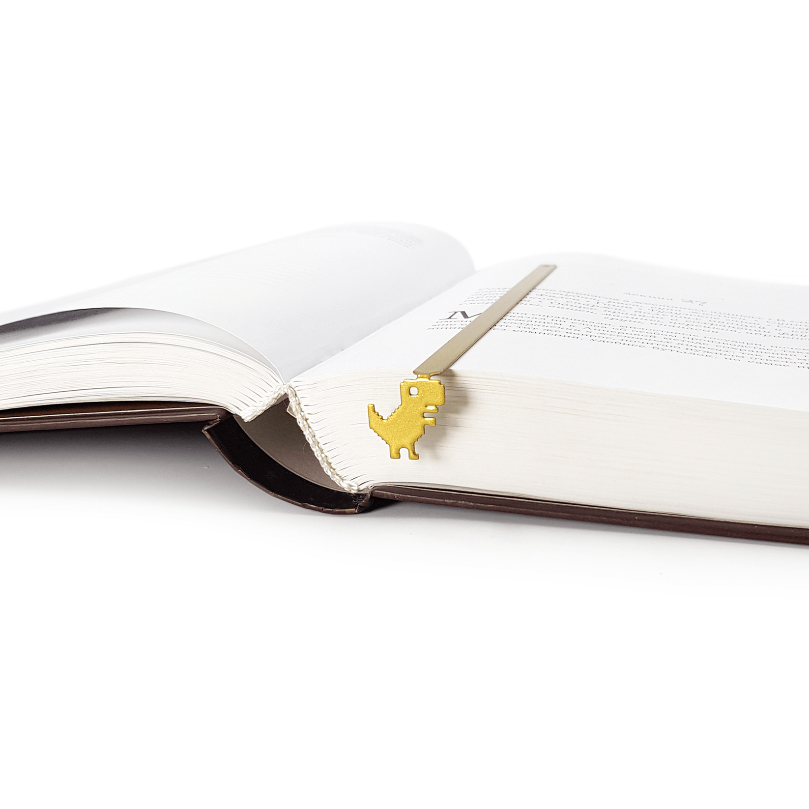 Little Dino metal bookmark in green marking a page in an open book