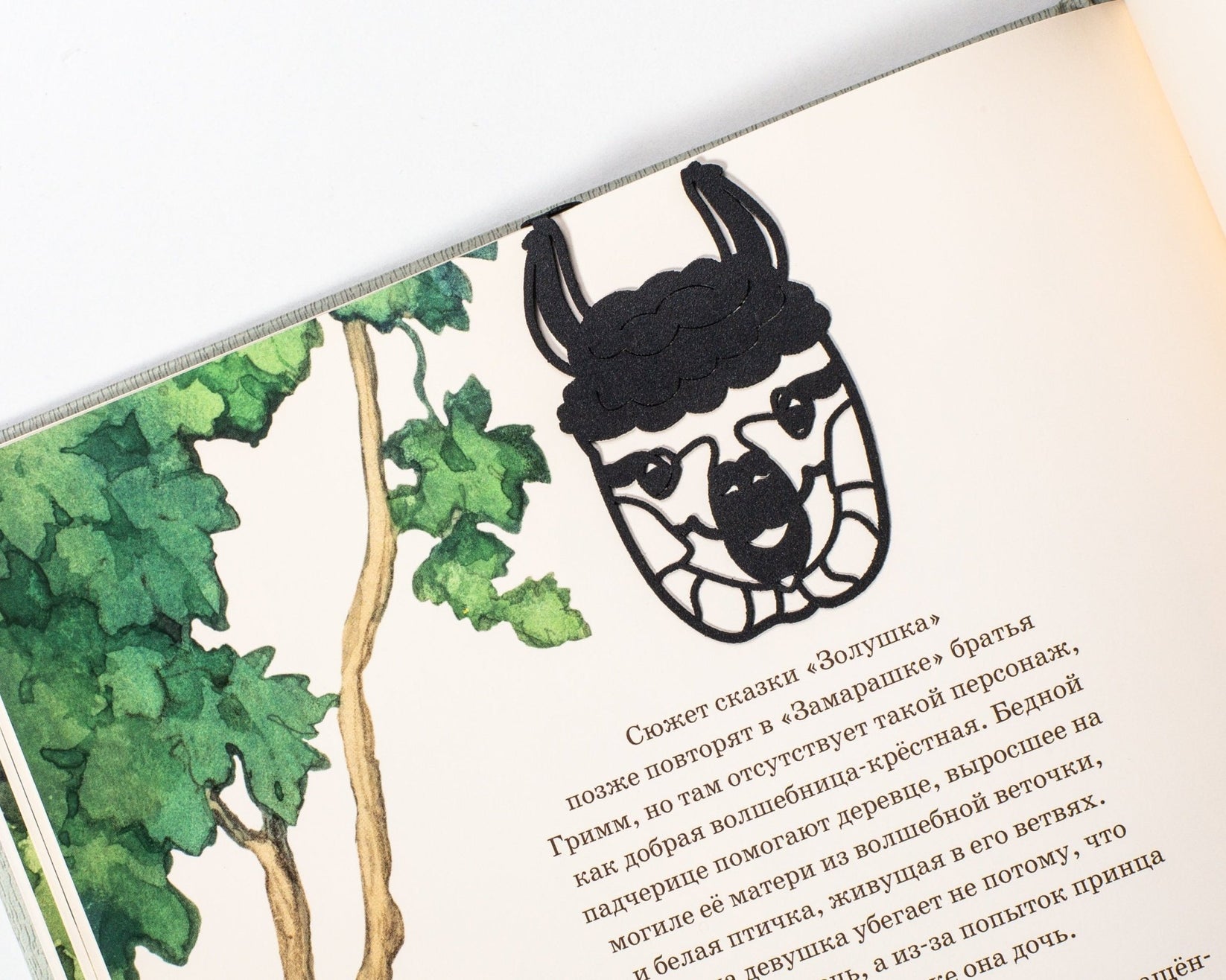 Llama metal bookmark marking a page in an illustrated book