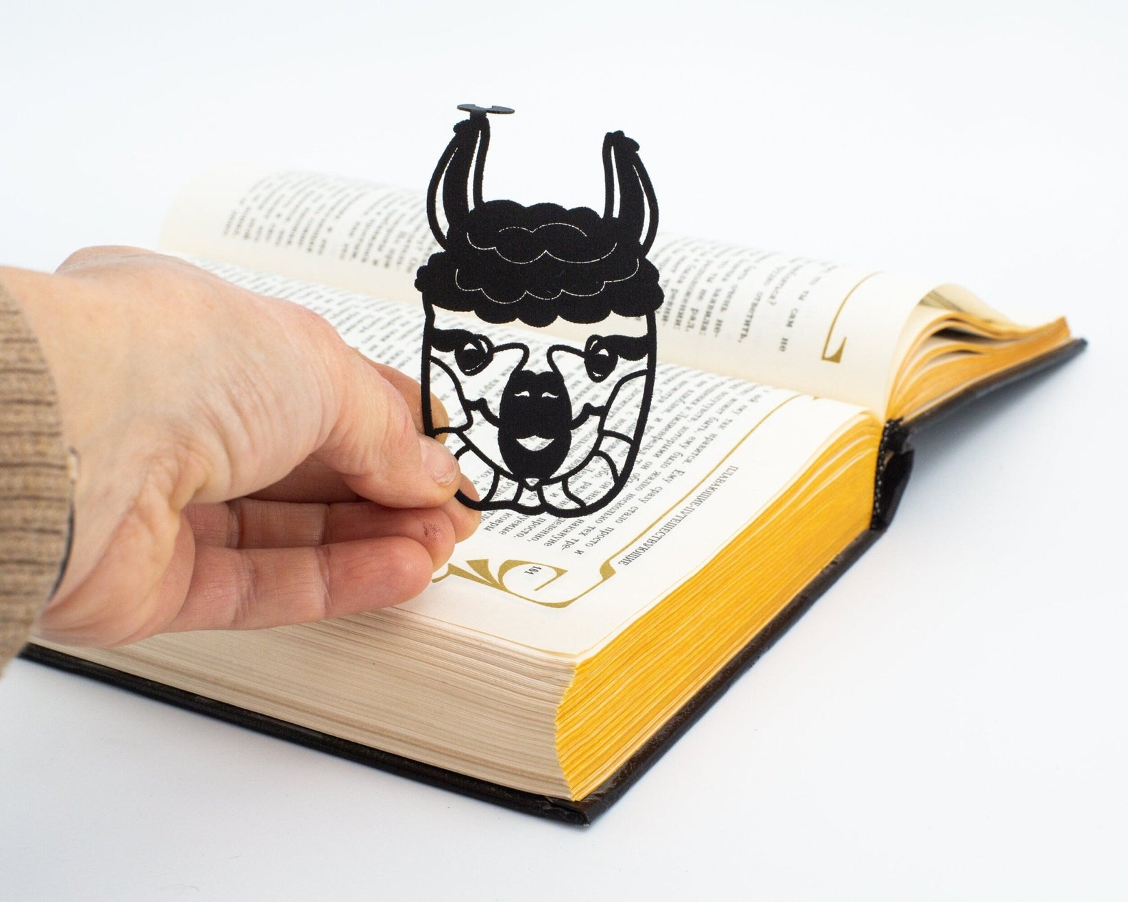 Llama metal bookmark held in a hand above an open book