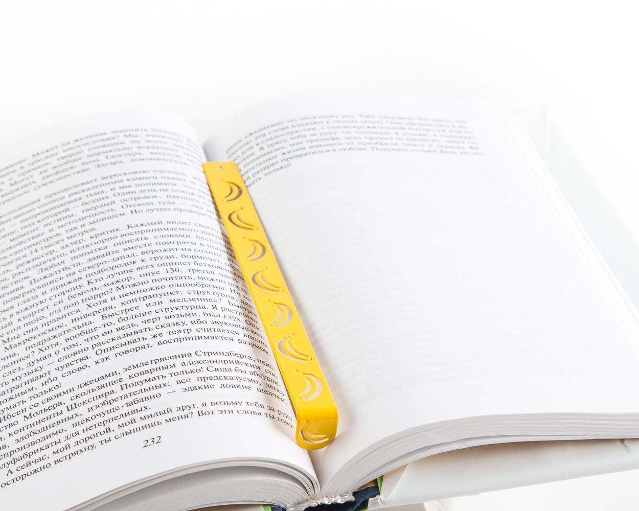 Many Bananas metal bookmark in gold marking a page in an open book