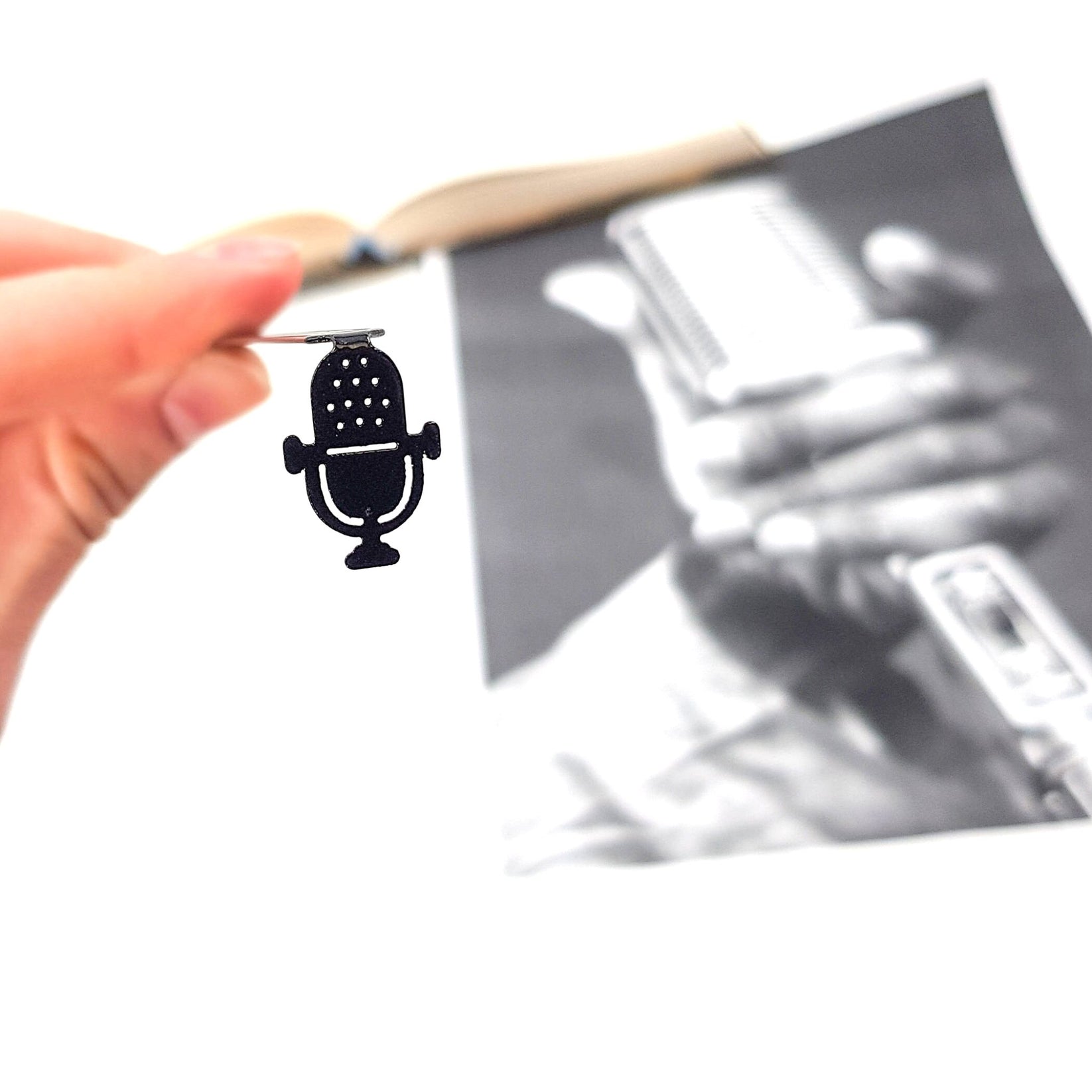 Microphone metal bookmark held in a hand above an open book