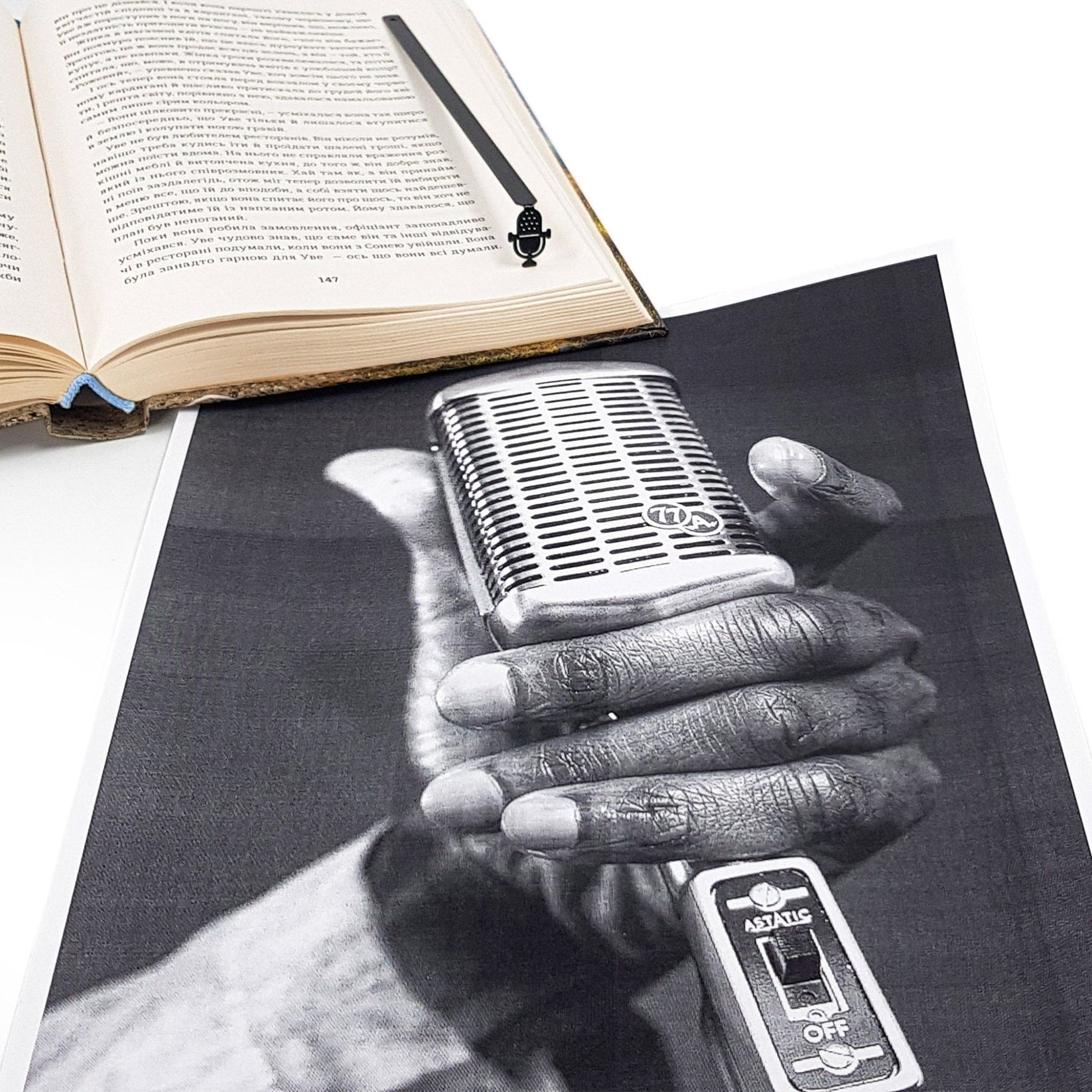 Microphone metal bookmark marking a page in an illustrated book