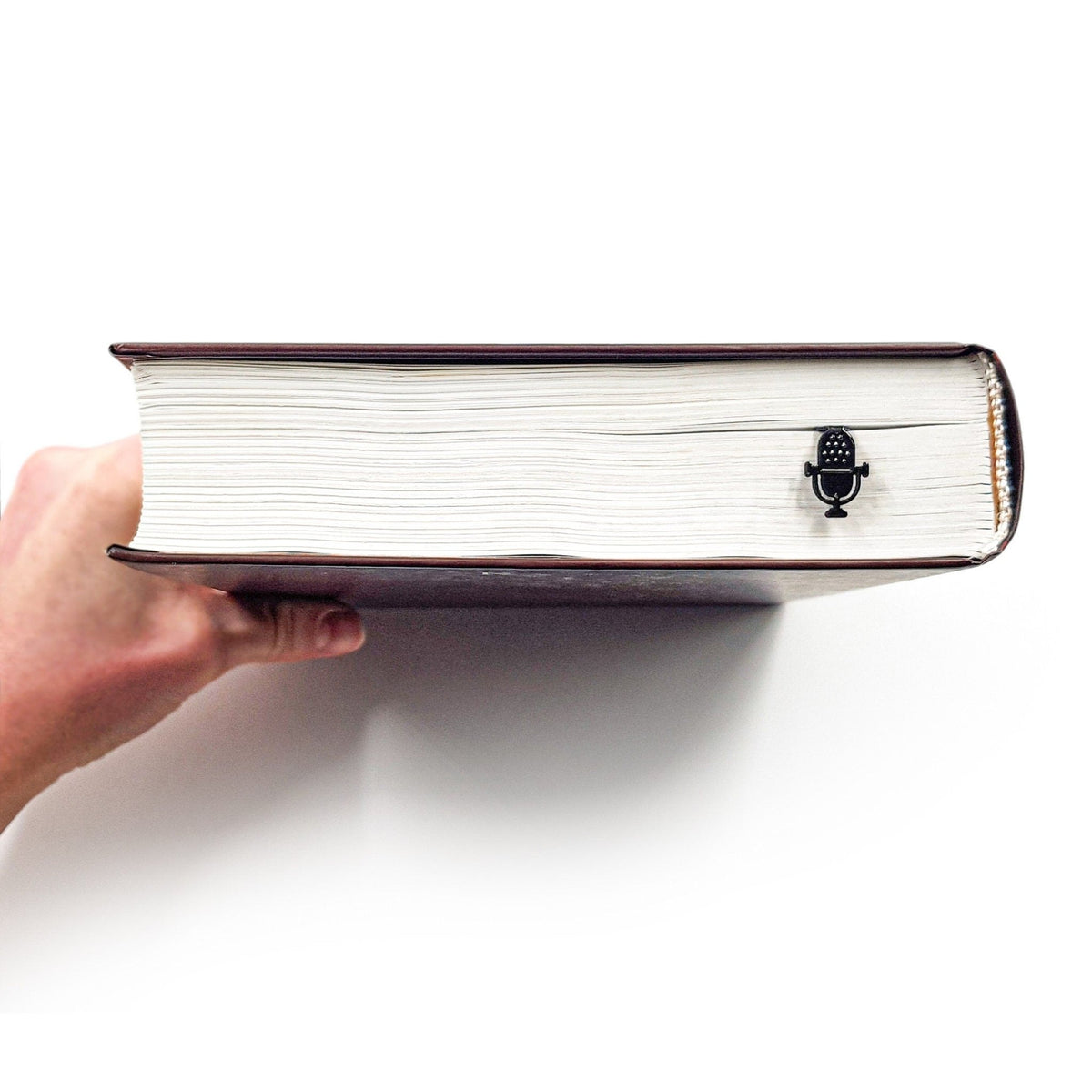 Microphone metal bookmark held in a hand to show its size