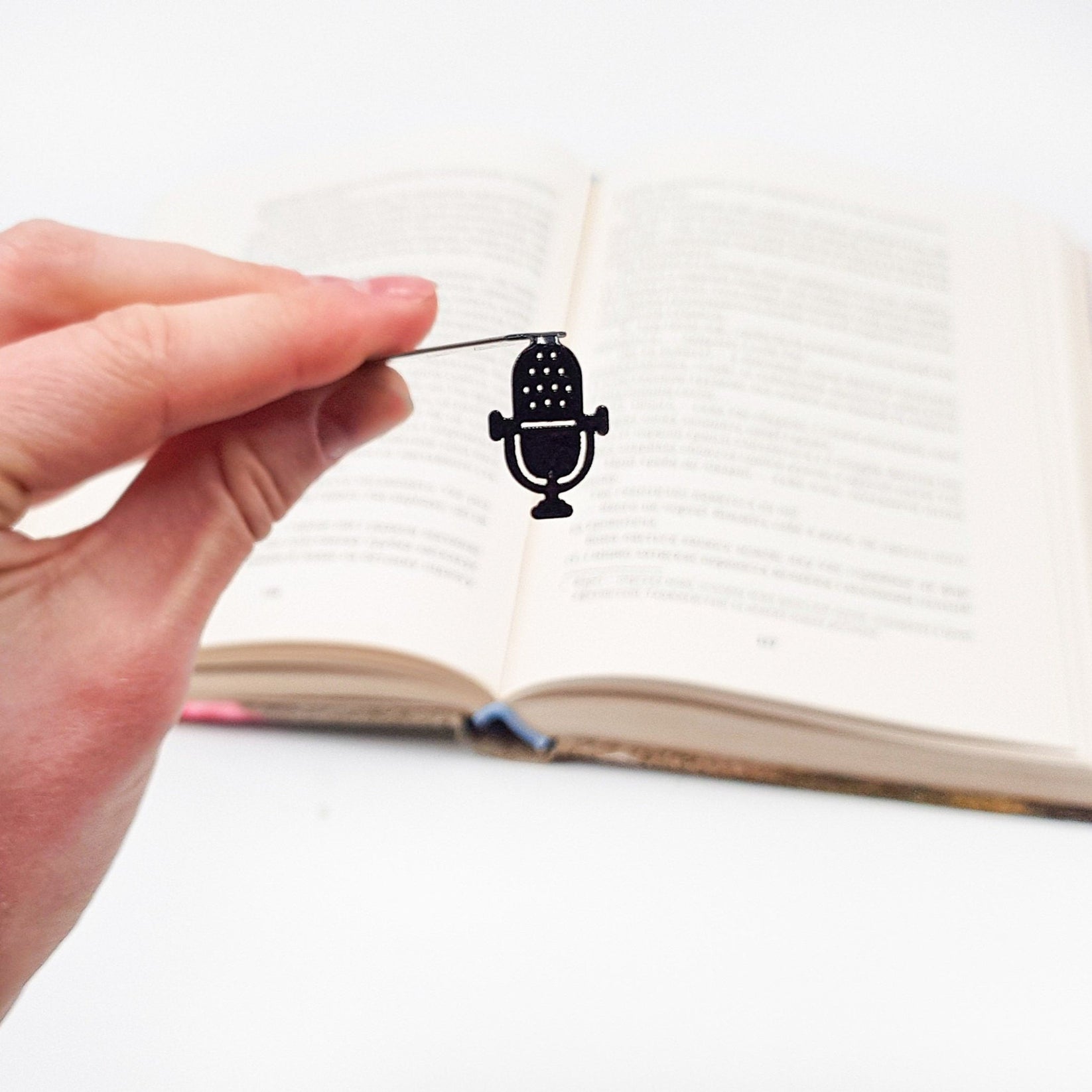 Microphone metal bookmark held up beside an open book