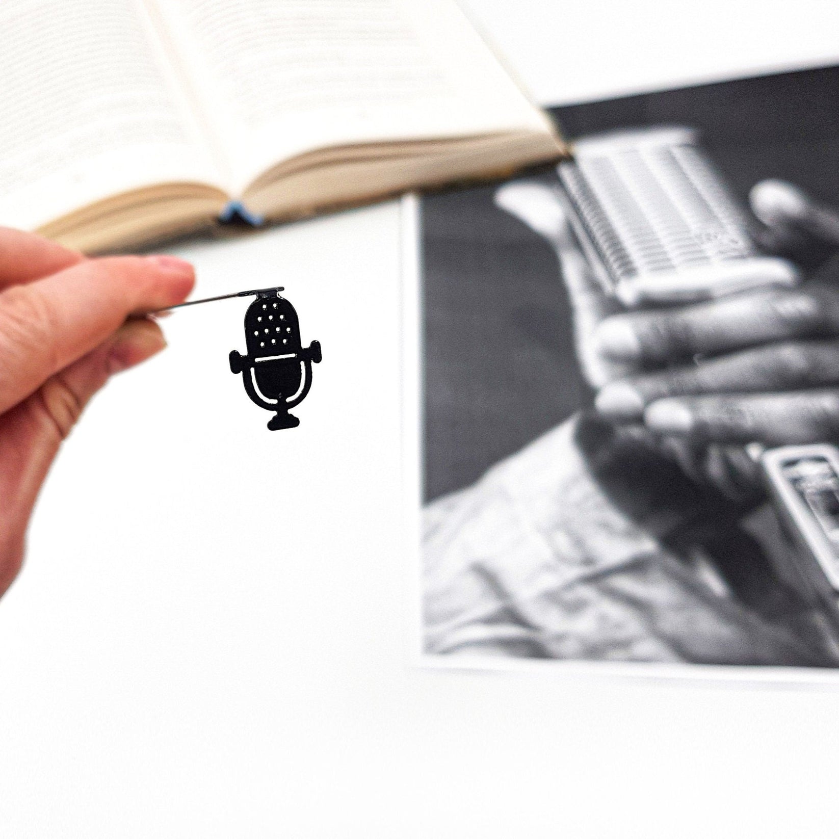 Microphone metal bookmark held over a book, seen from the front