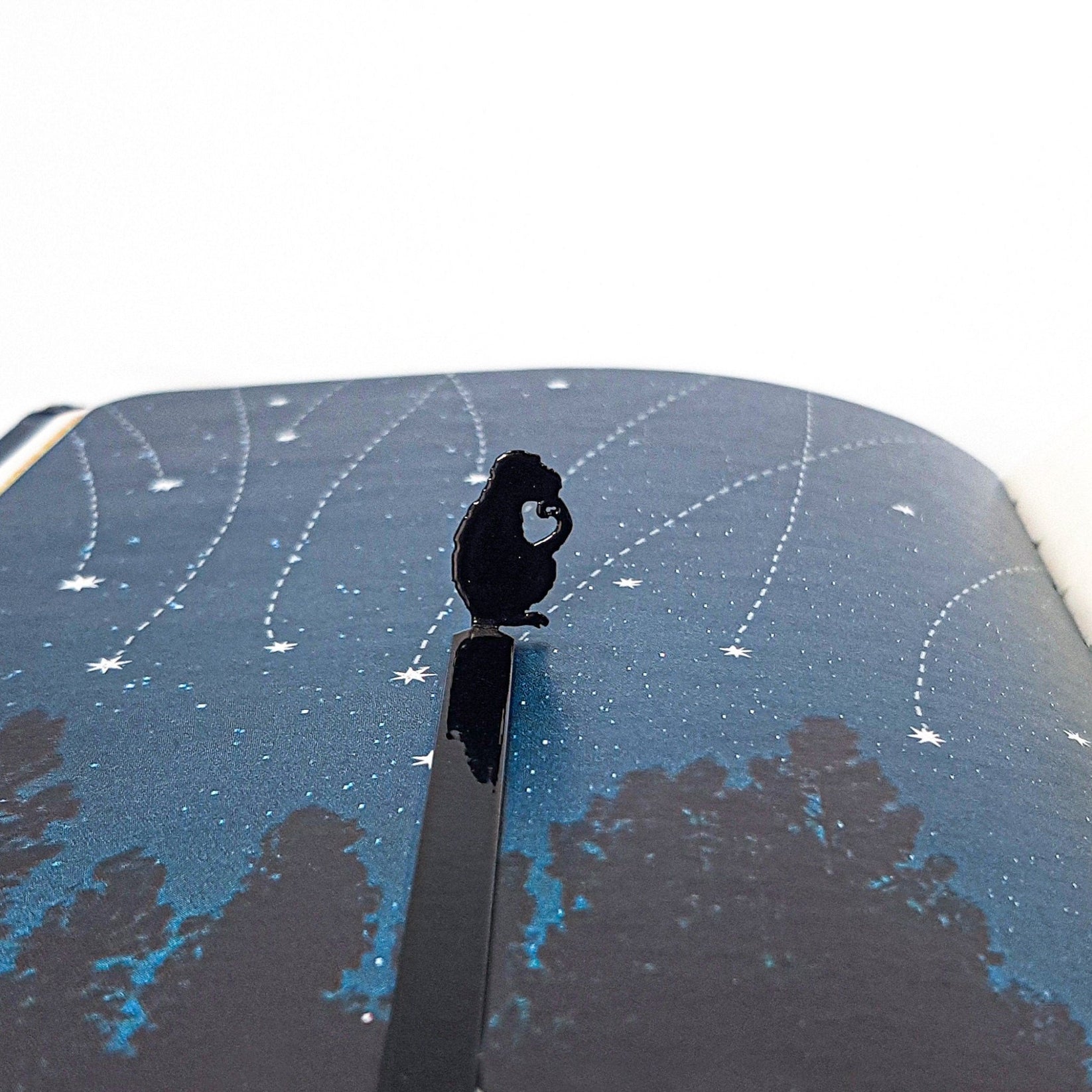 Monkey the Thinker metal bookmark against a coloured backdrop