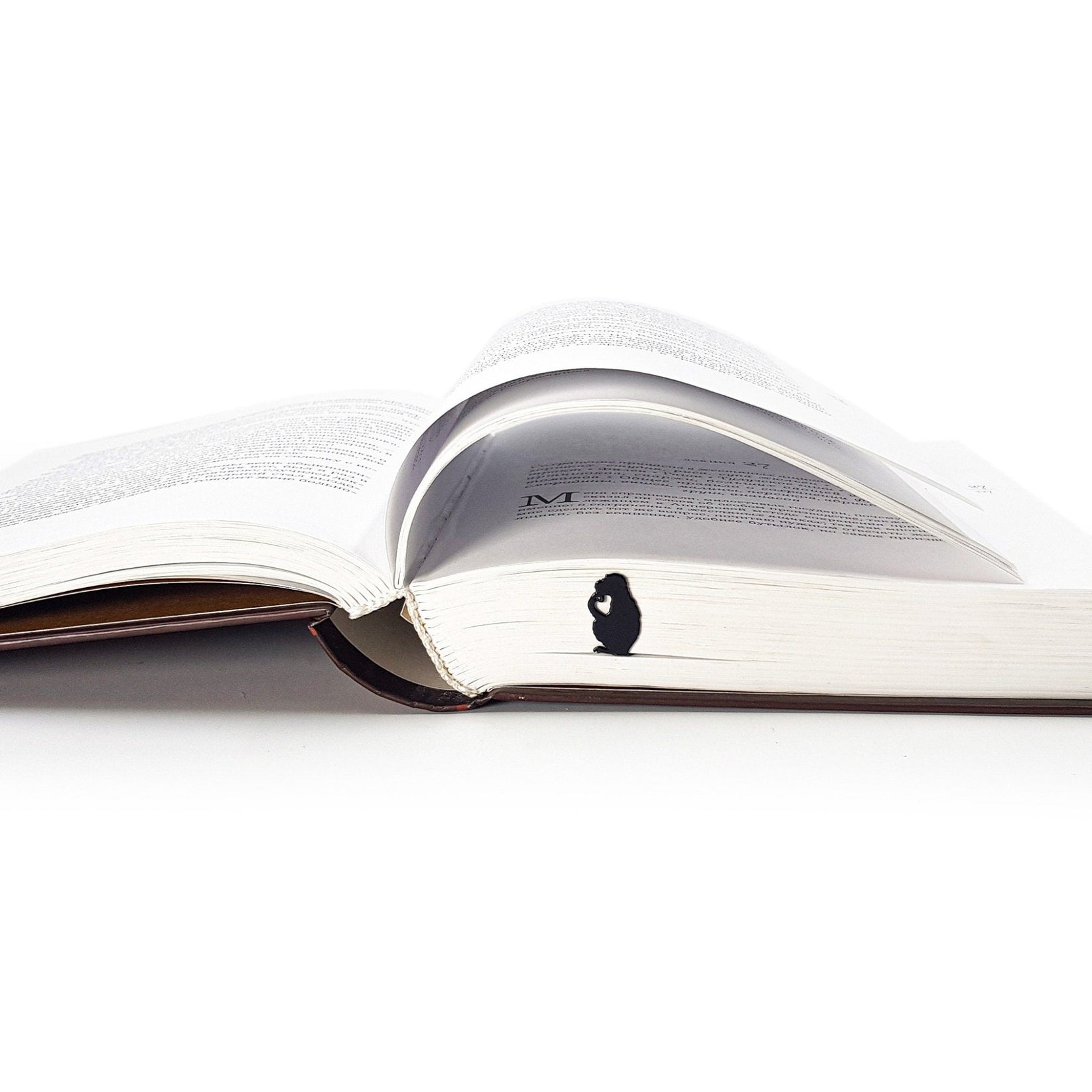 Monkey the Thinker metal bookmark resting on the pages of an open book