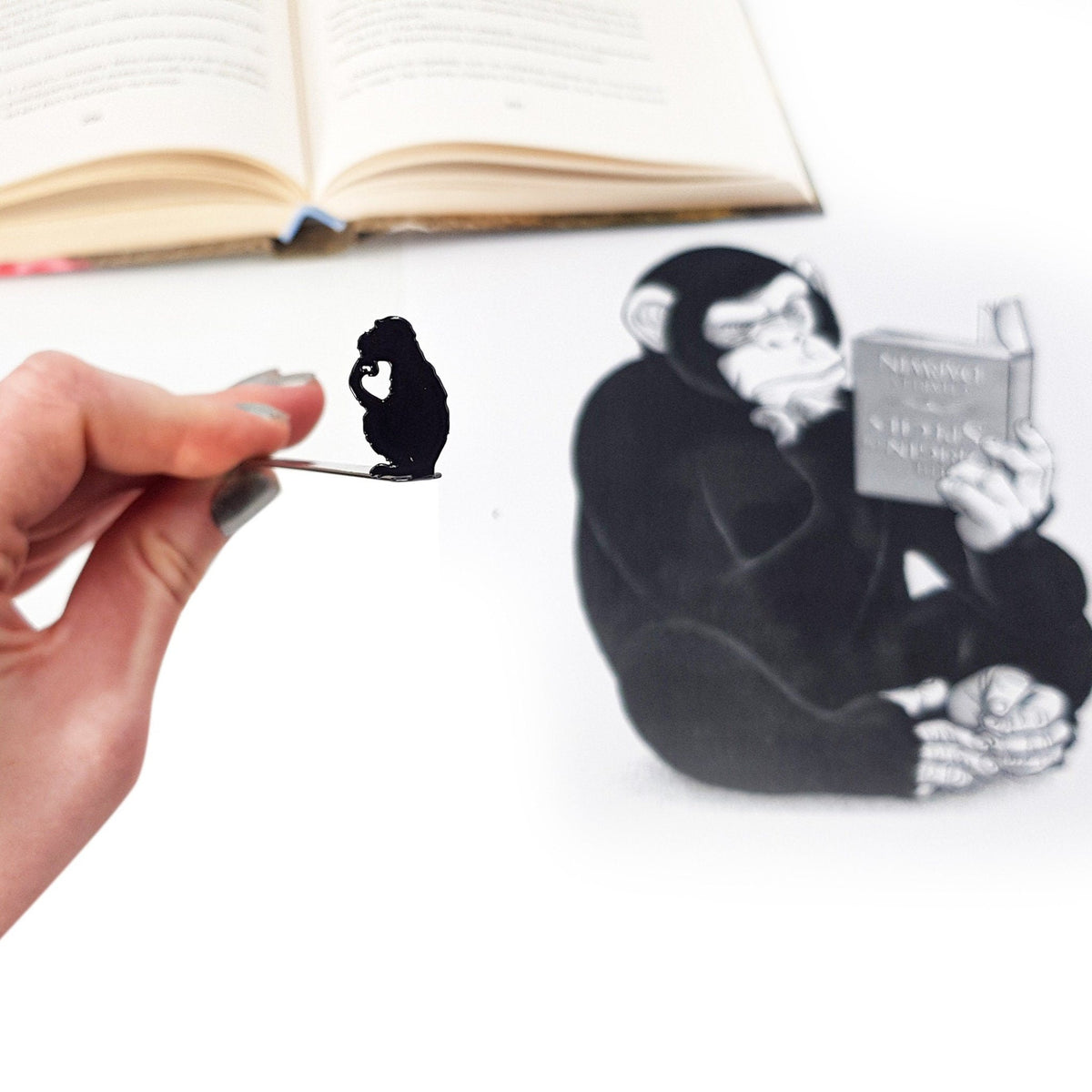 Monkey the Thinker metal bookmark marking a page in an illustrated book