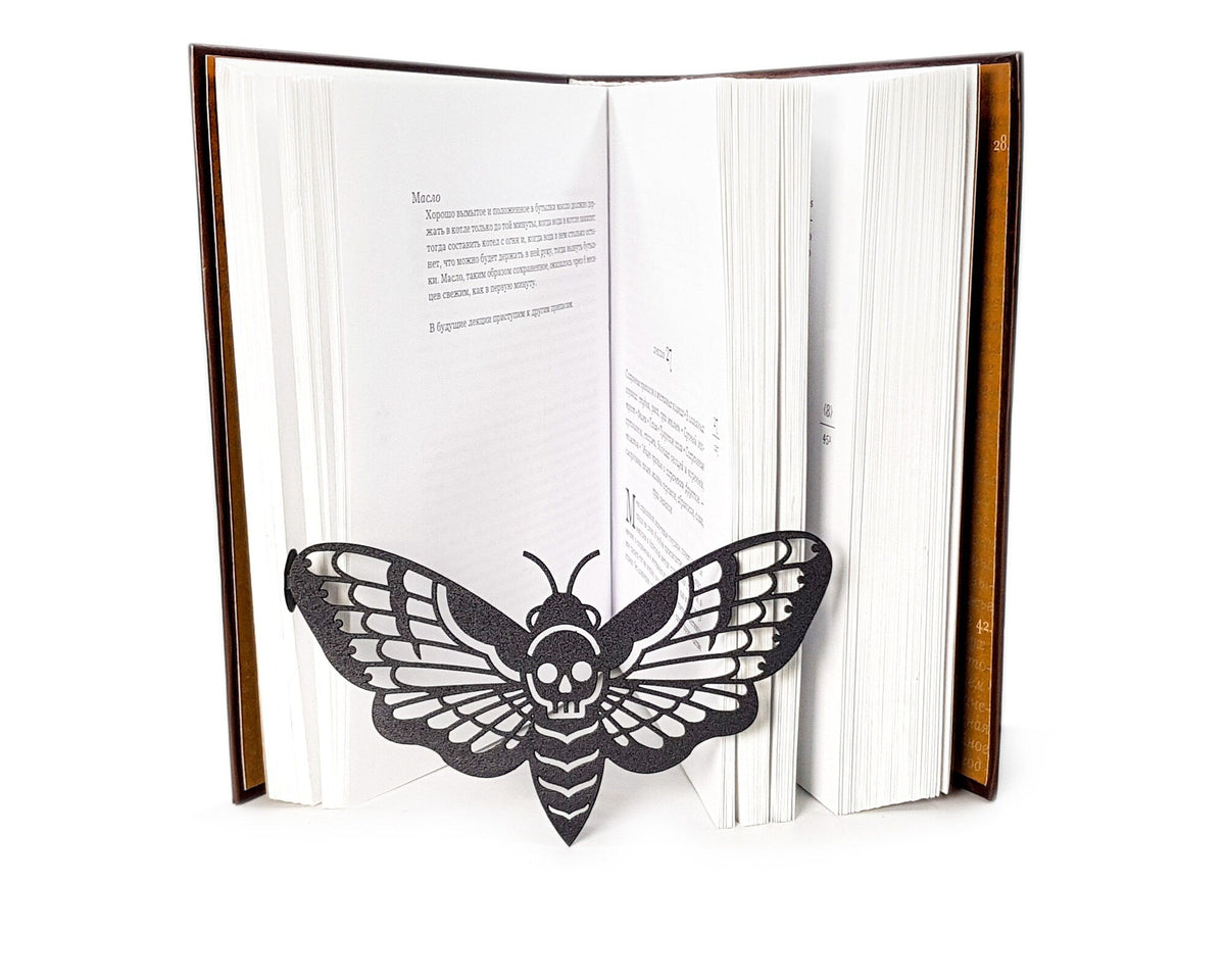 Moth of Death metal bookmark lying across the pages of an open book, view 7