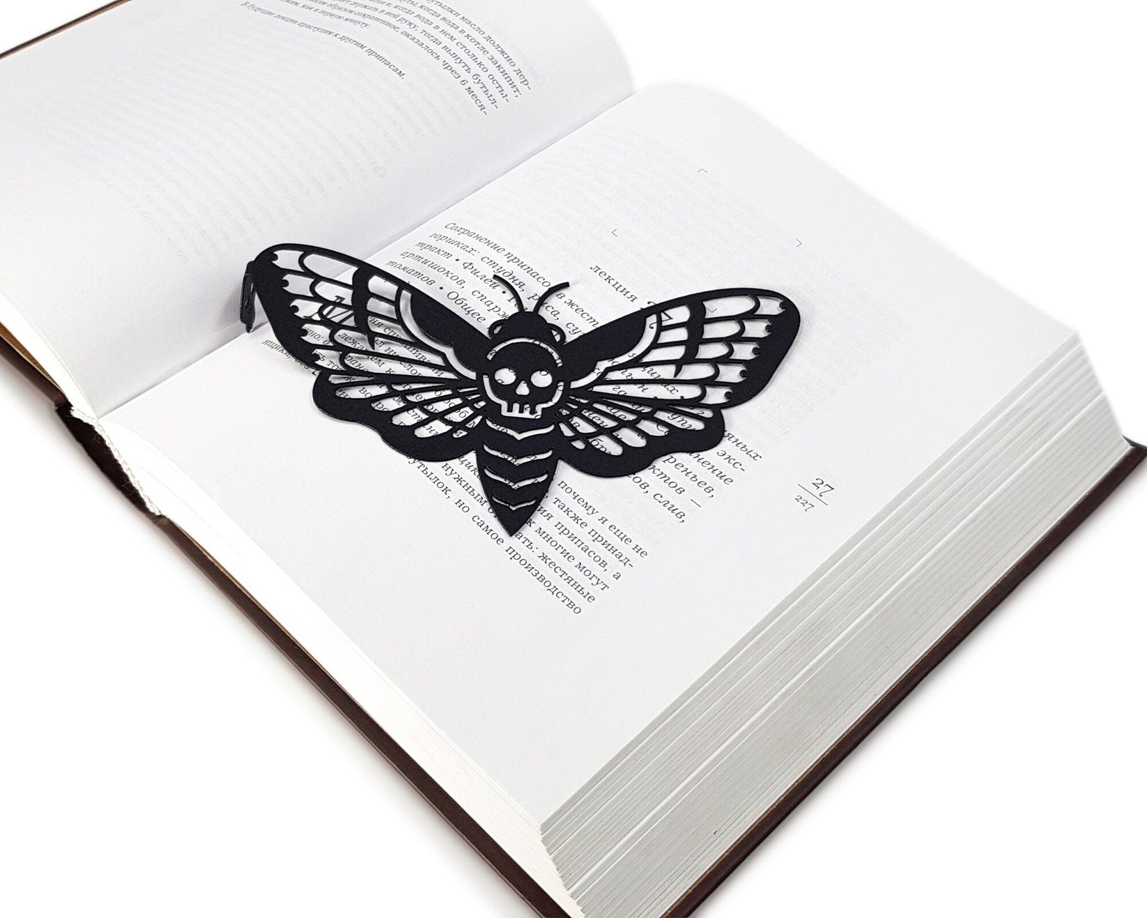 Moth of Death metal bookmark set into the gutter of an open book