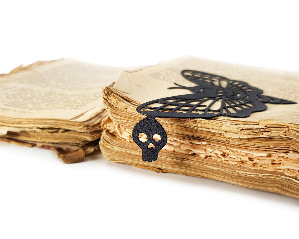 Moth of Death metal bookmark marking a page in an open book