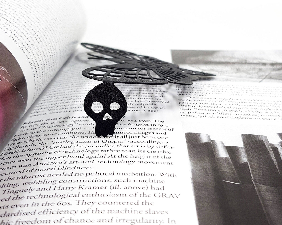 Moth of Death metal bookmark on an illustrated page