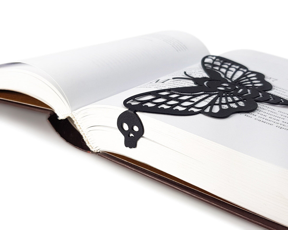 Moth of Death metal bookmark resting on the pages of an open book, view 5