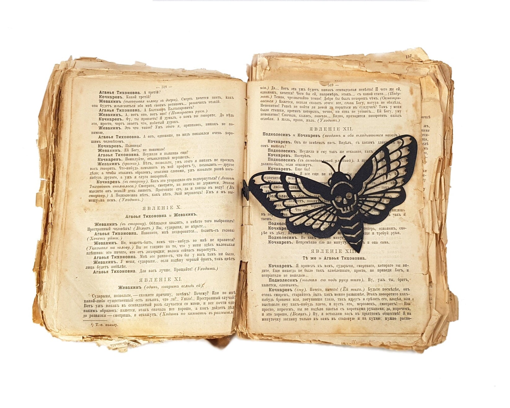 Moth of Death metal bookmark resting on the pages of an open book