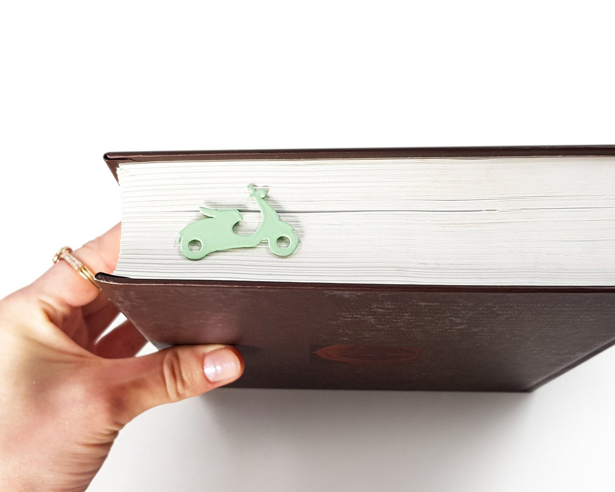 Motor Scooter metal bookmark in green held in a hand above an open book