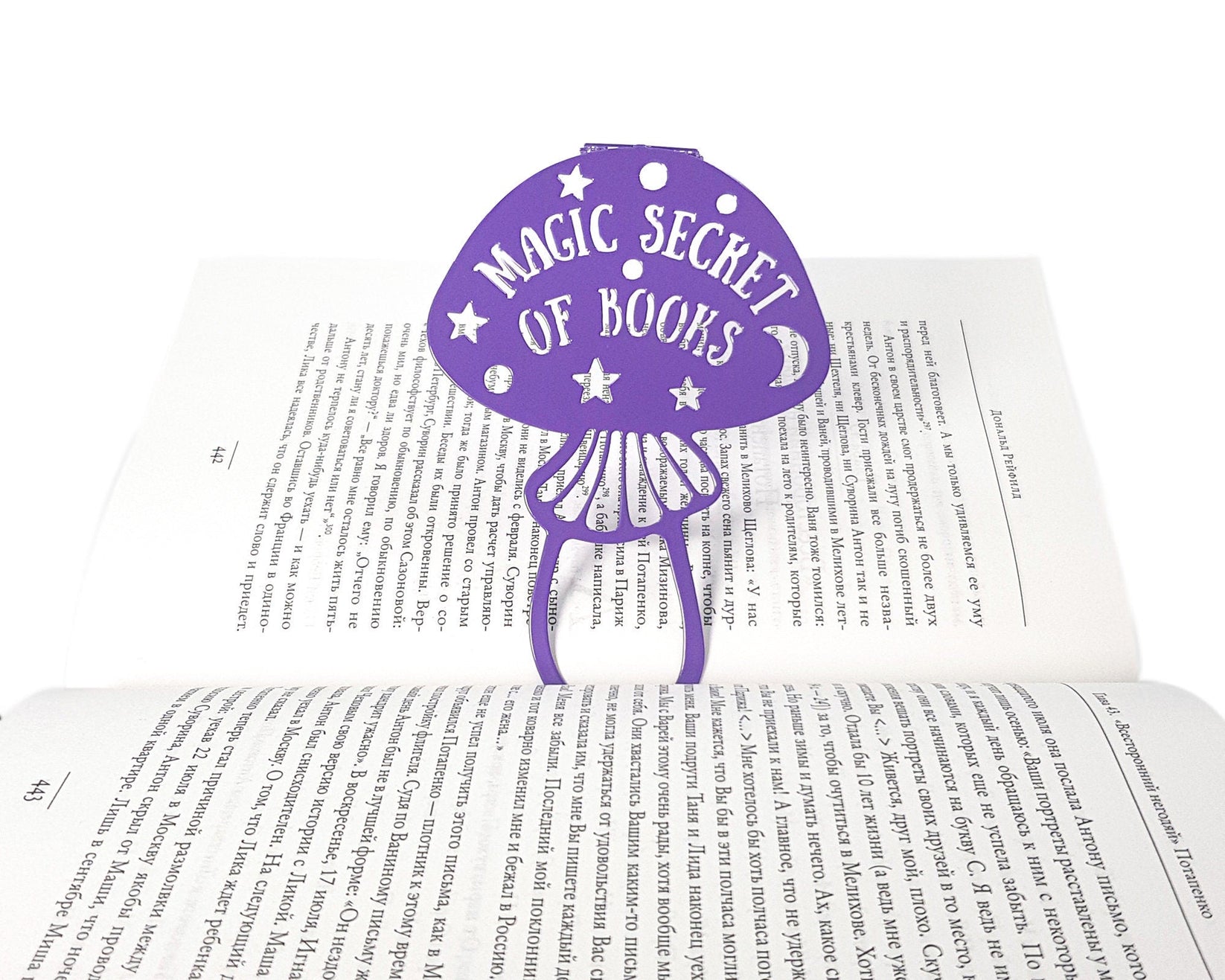 Mushroom metal bookmark in blue marking a page in an open book