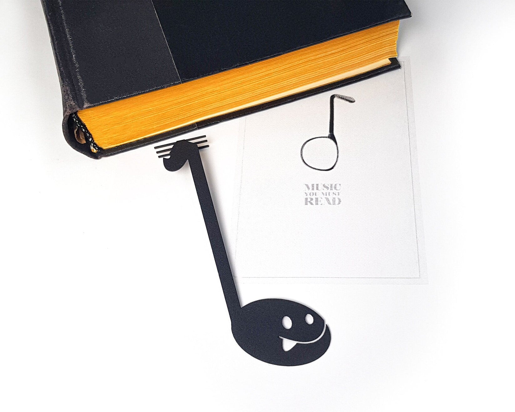 Musical Note metal bookmark seen from the edge of a closed book