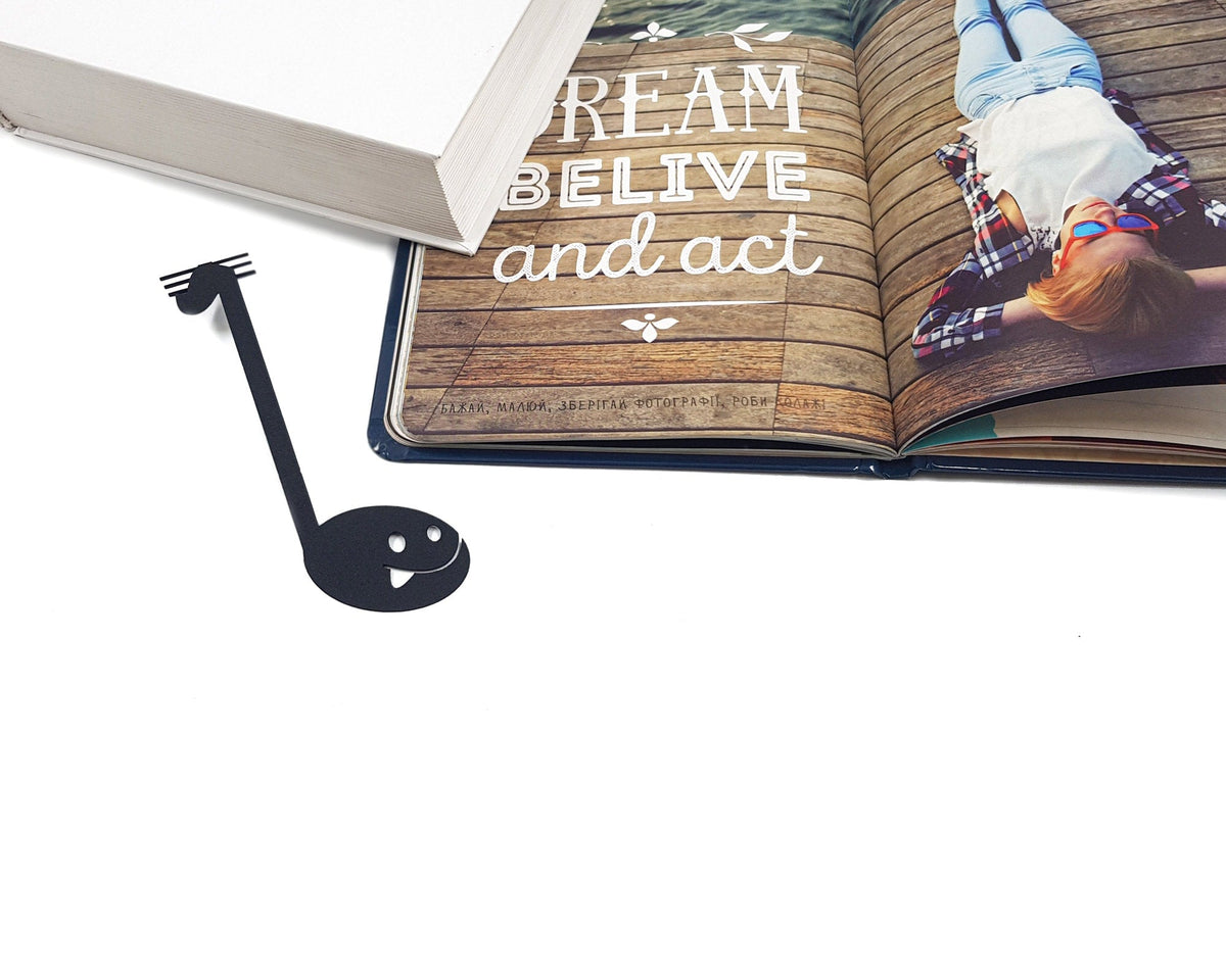Musical Note metal bookmark marking a page in an illustrated book