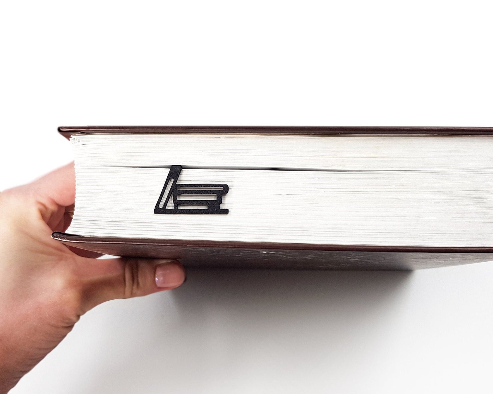 My Bookshelf metal bookmark held in a hand above an open book