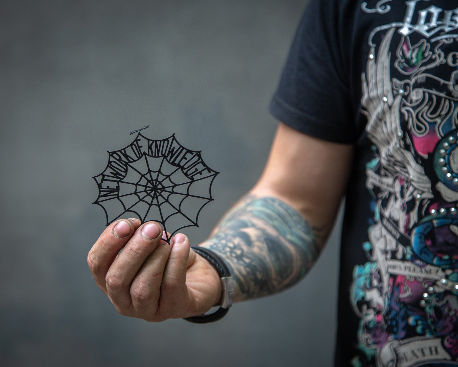 Network of Knowledge metal bookmark — hand holding bookmark on dark background