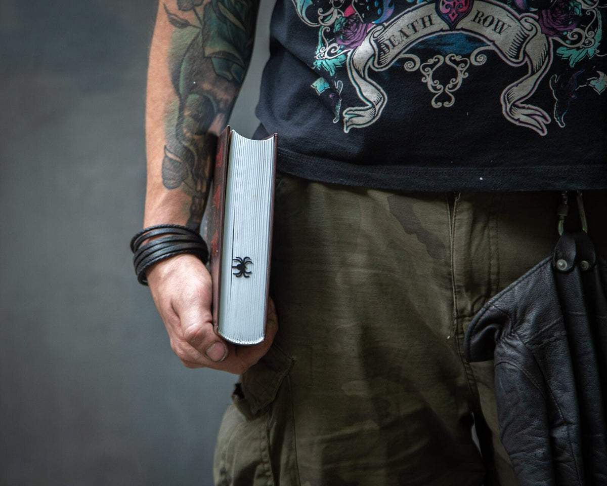 Network of Knowledge metal bookmark — tattooed man holding bookmark, dark studio photo