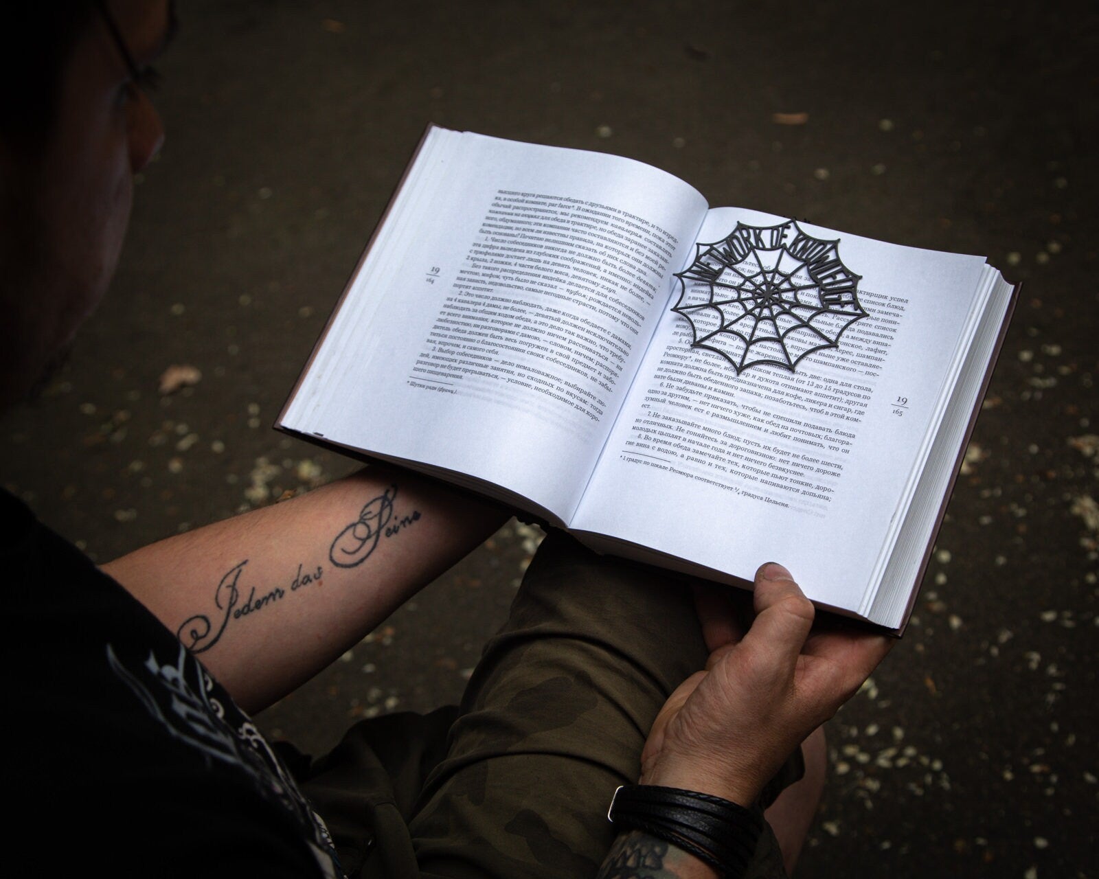 Network of Knowledge metal bookmark held up beside an open book