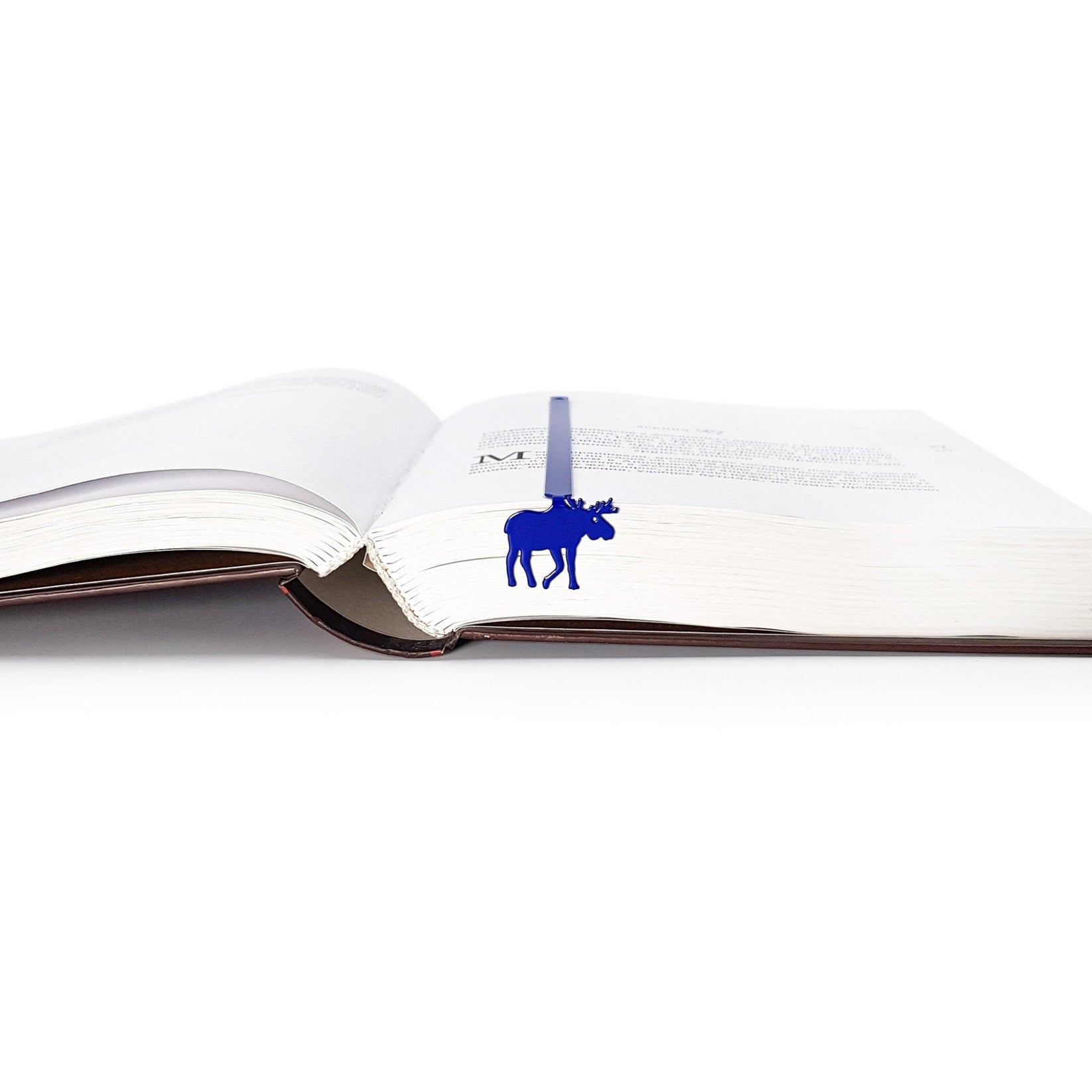 Norwegian Moose metal bookmark in blue lying across the pages of an open book