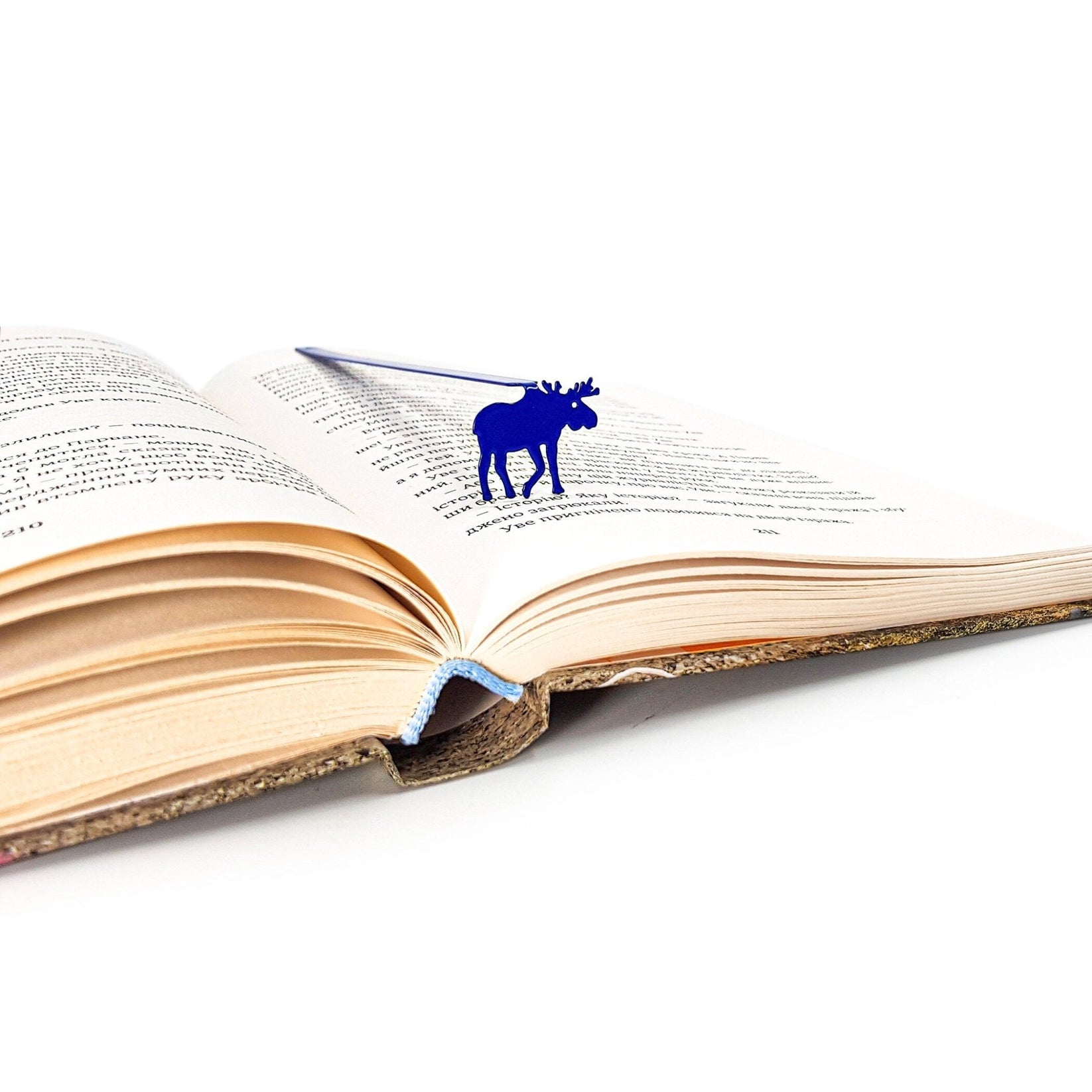 Norwegian Moose metal bookmark in blue resting on the pages of an open book