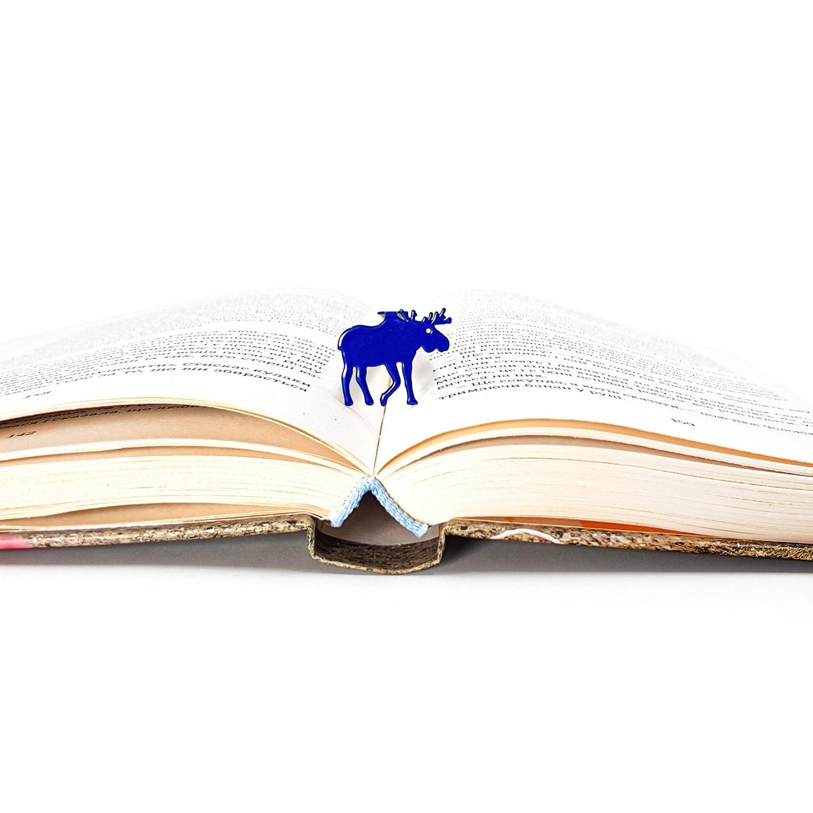 Norwegian Moose metal bookmark in blue set into the gutter of an open book