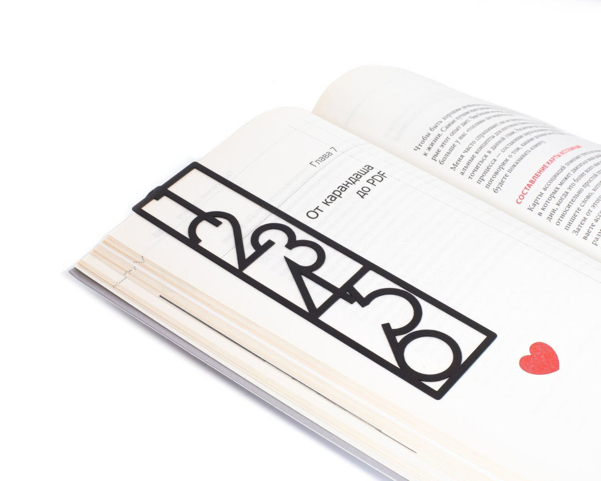 Numbers Bauhaus Style metal bookmark lying across the pages of an open book