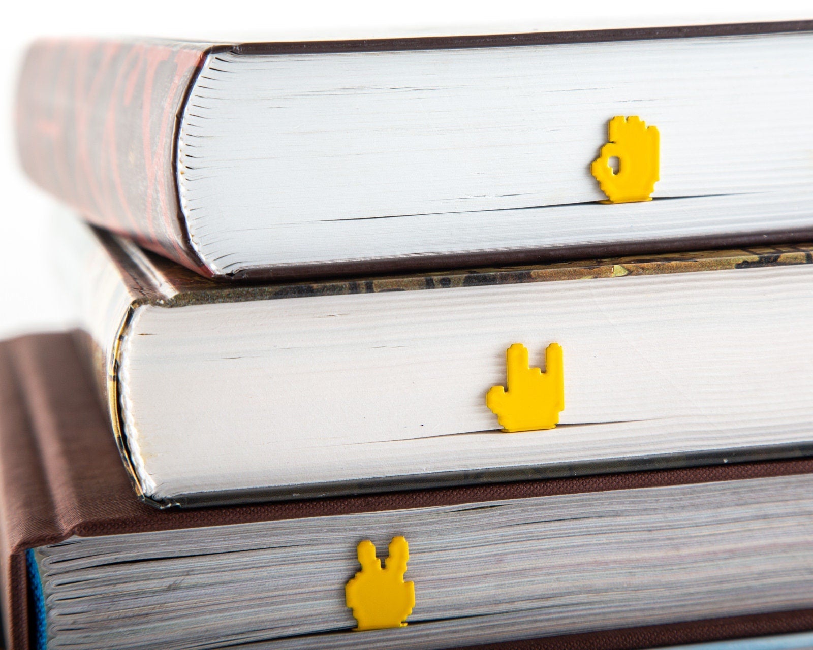 OK Sign Pixel Style metal bookmark in gold lying on a stack of white books