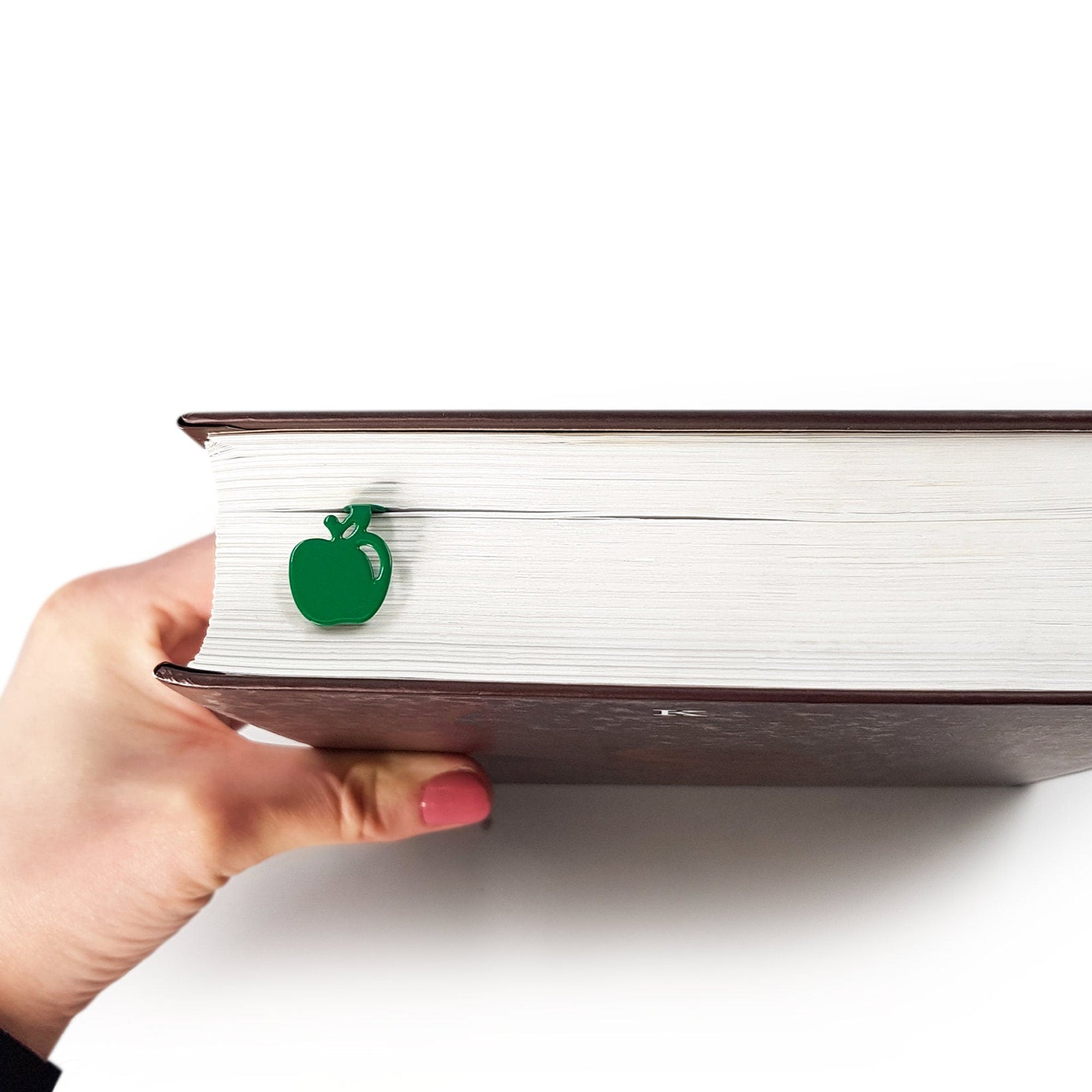 Paradise Apple' metal bookmark in green held up beside an open book