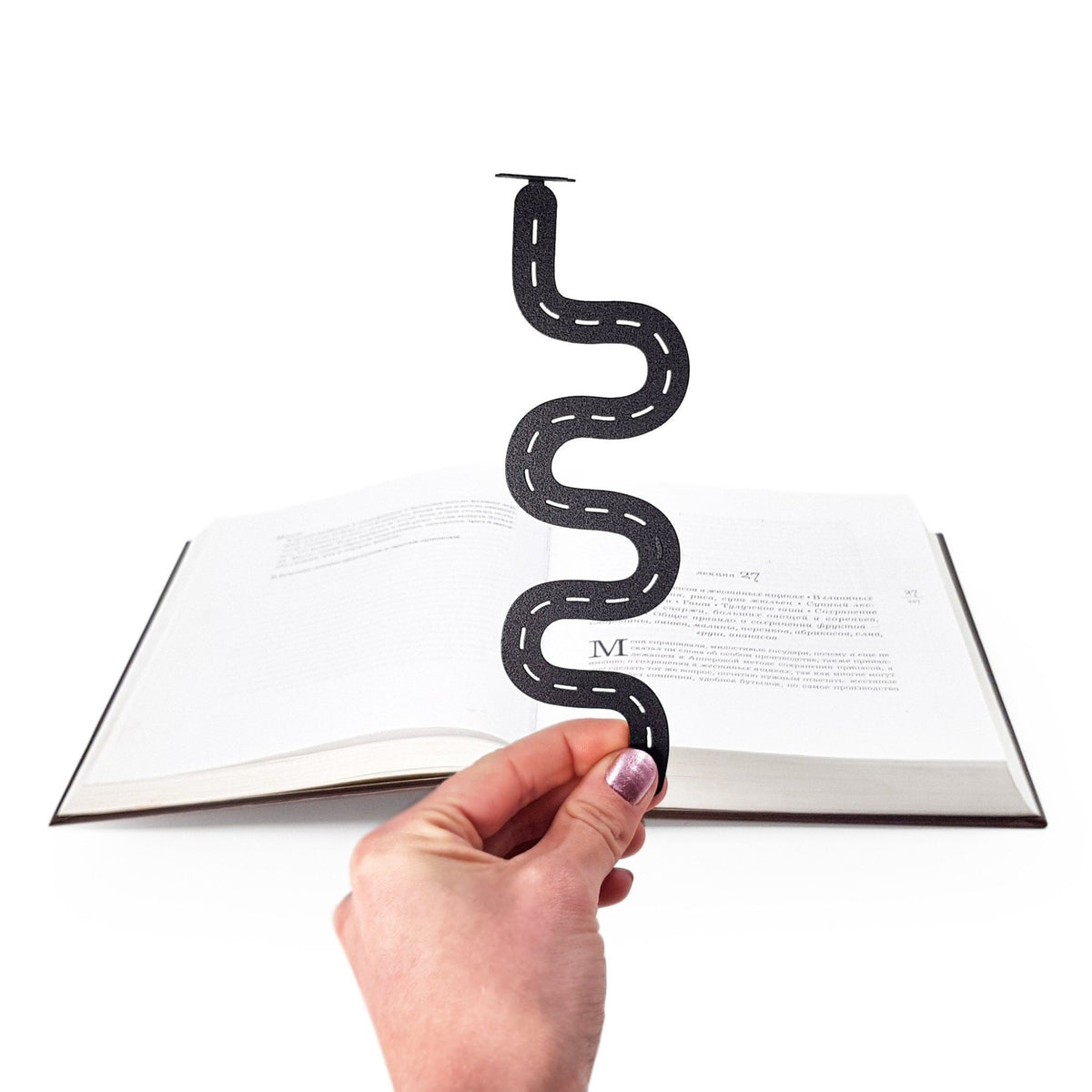 Peace Trip metal bookmark held in a hand above an open book
