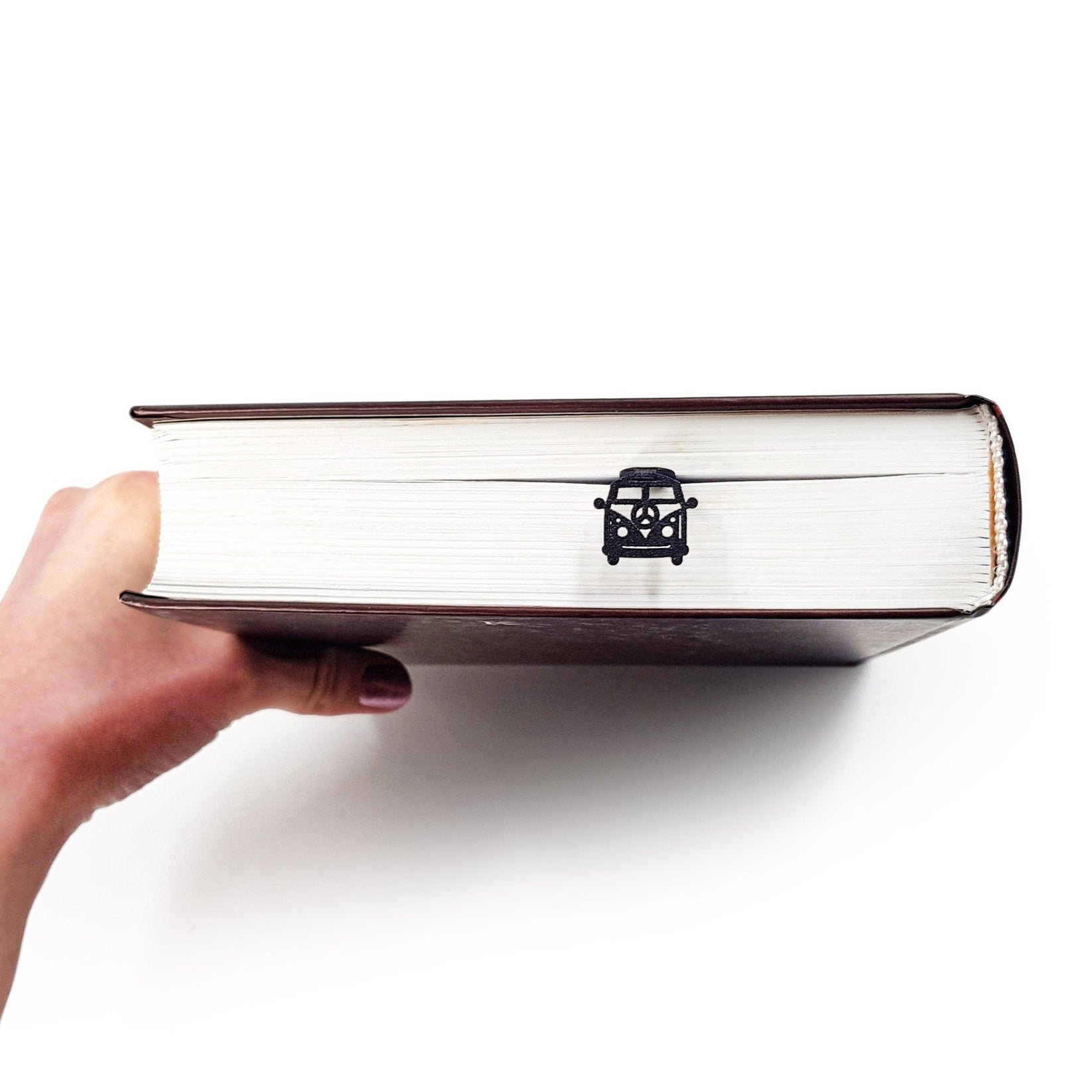 Peace Trip metal bookmark held up beside an open book