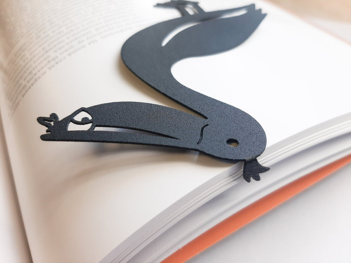 Pelican metal bookmark resting on the pages of an open book