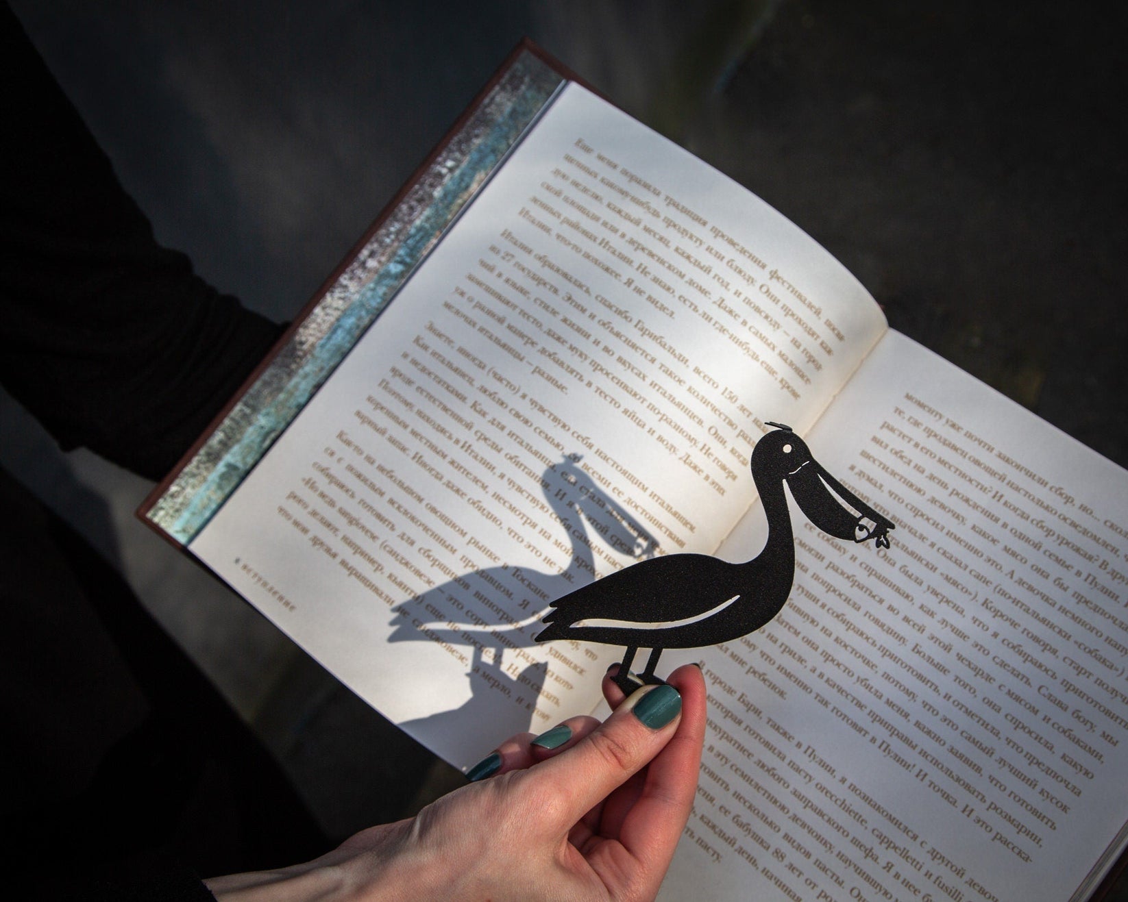 Pelican metal bookmark held up beside an open book