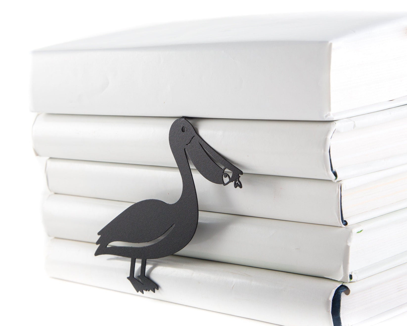 Pelican metal bookmark lying on a stack of white books