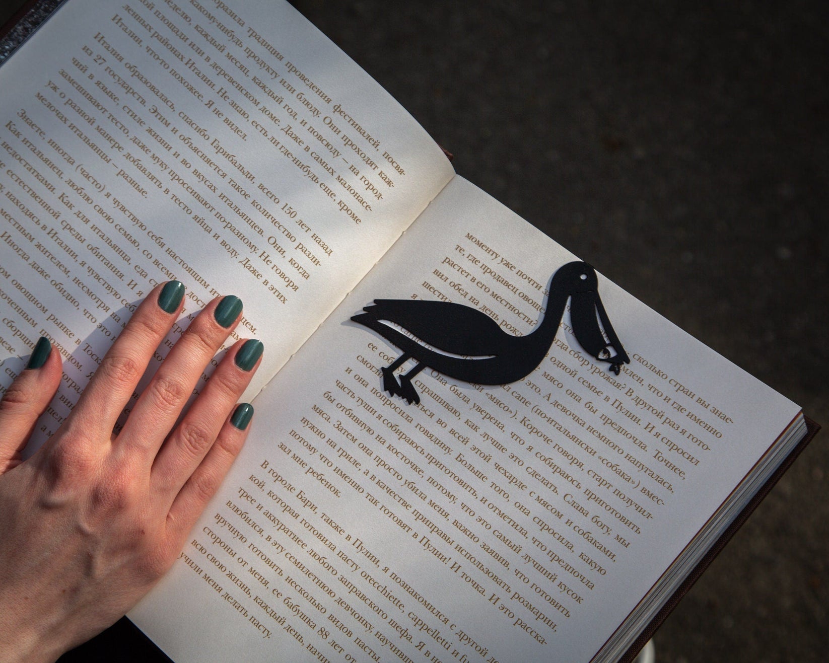 Pelican metal bookmark held in a hand to show its size