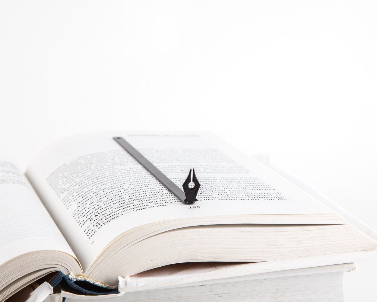Pen Point metal bookmark resting on the pages of an open book