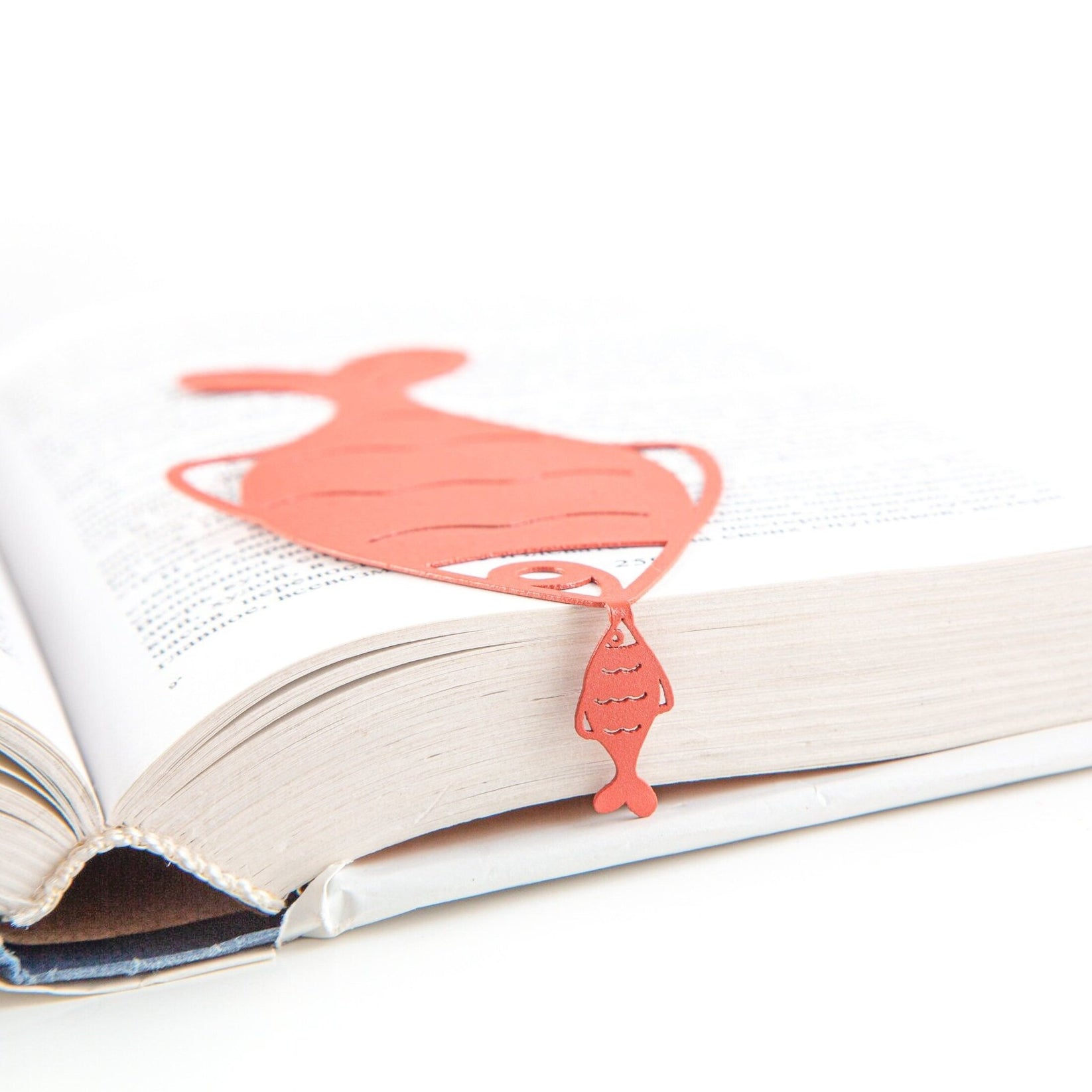 Perch metal bookmark in red marking a page in an open book