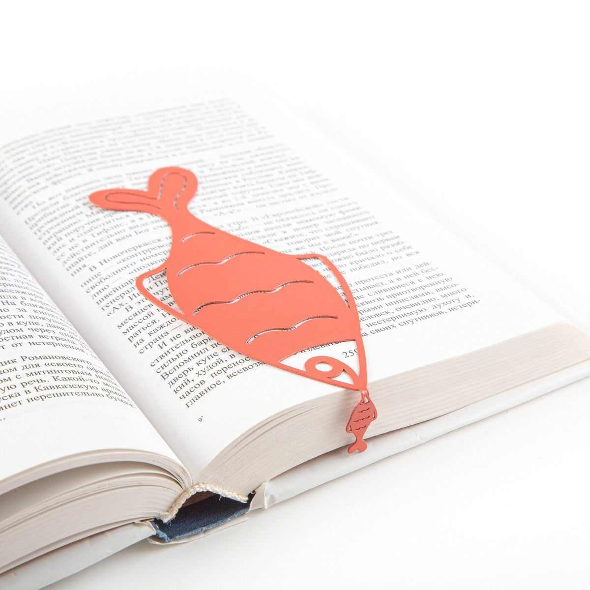 Perch metal bookmark in red lying across the pages of an open book