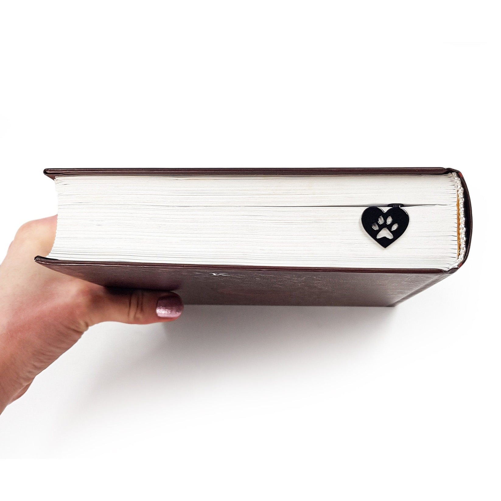 Pet Love metal bookmark held in a hand above an open book