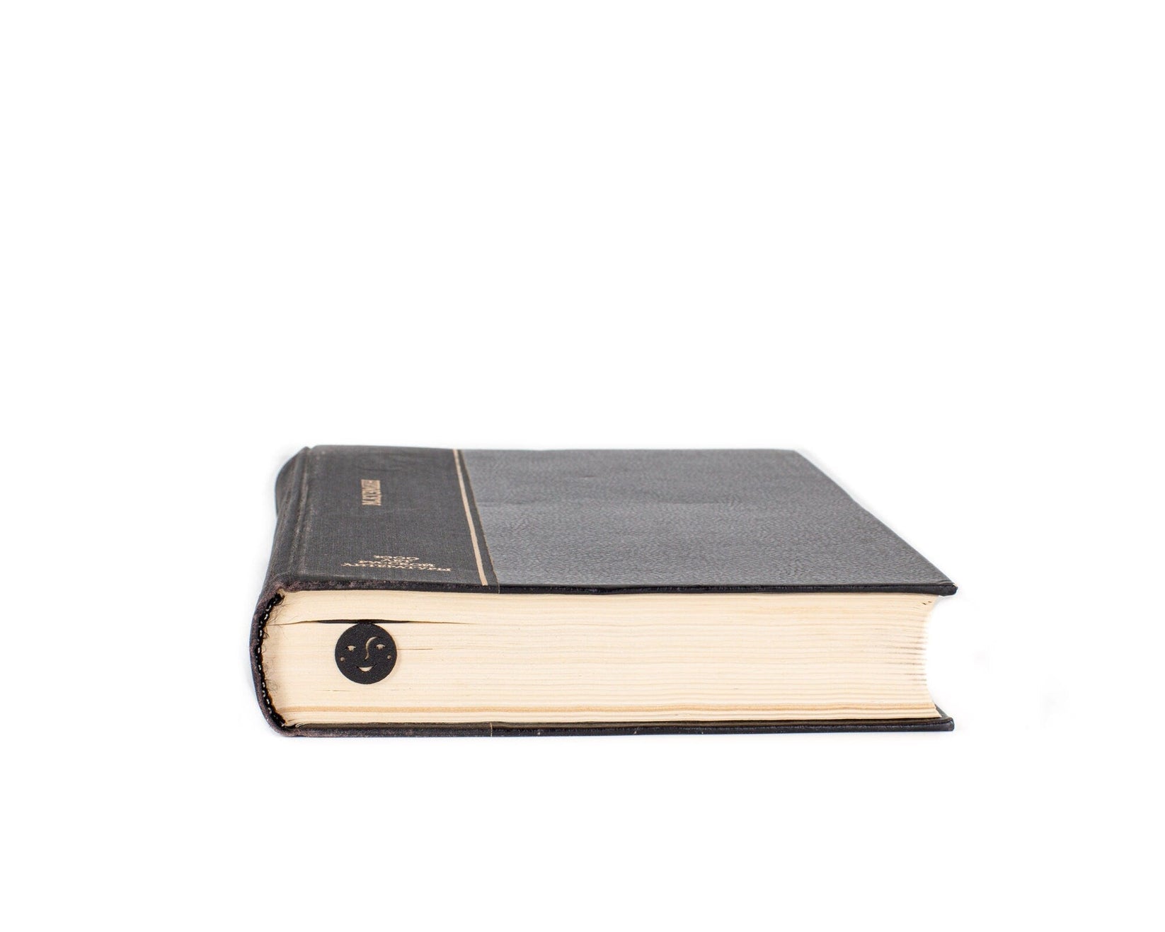 Phases of the Moon metal bookmark in a closed book, only its top showing above the pages