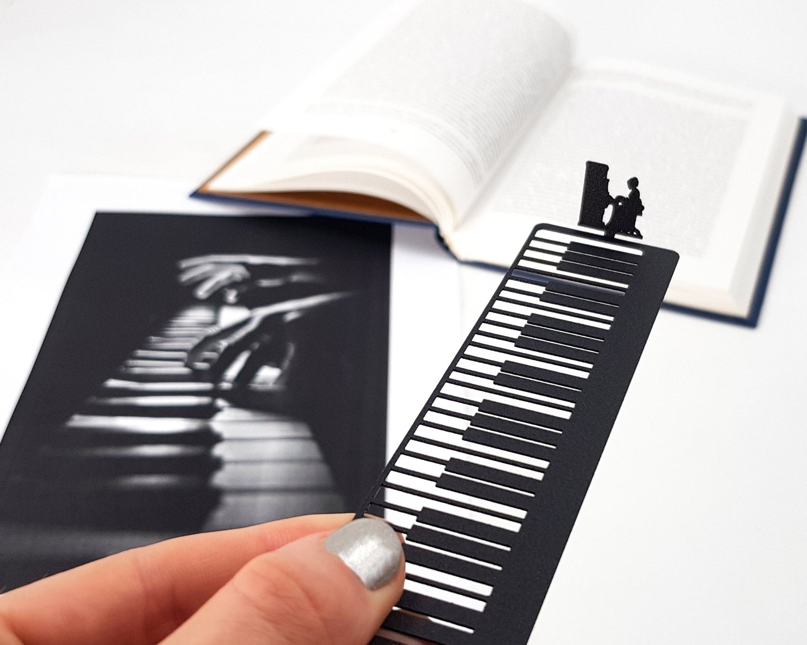 Piano Player metal bookmark marking a page in an illustrated book