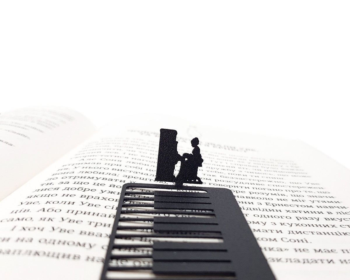 Piano Player metal bookmark marking a page in an open book