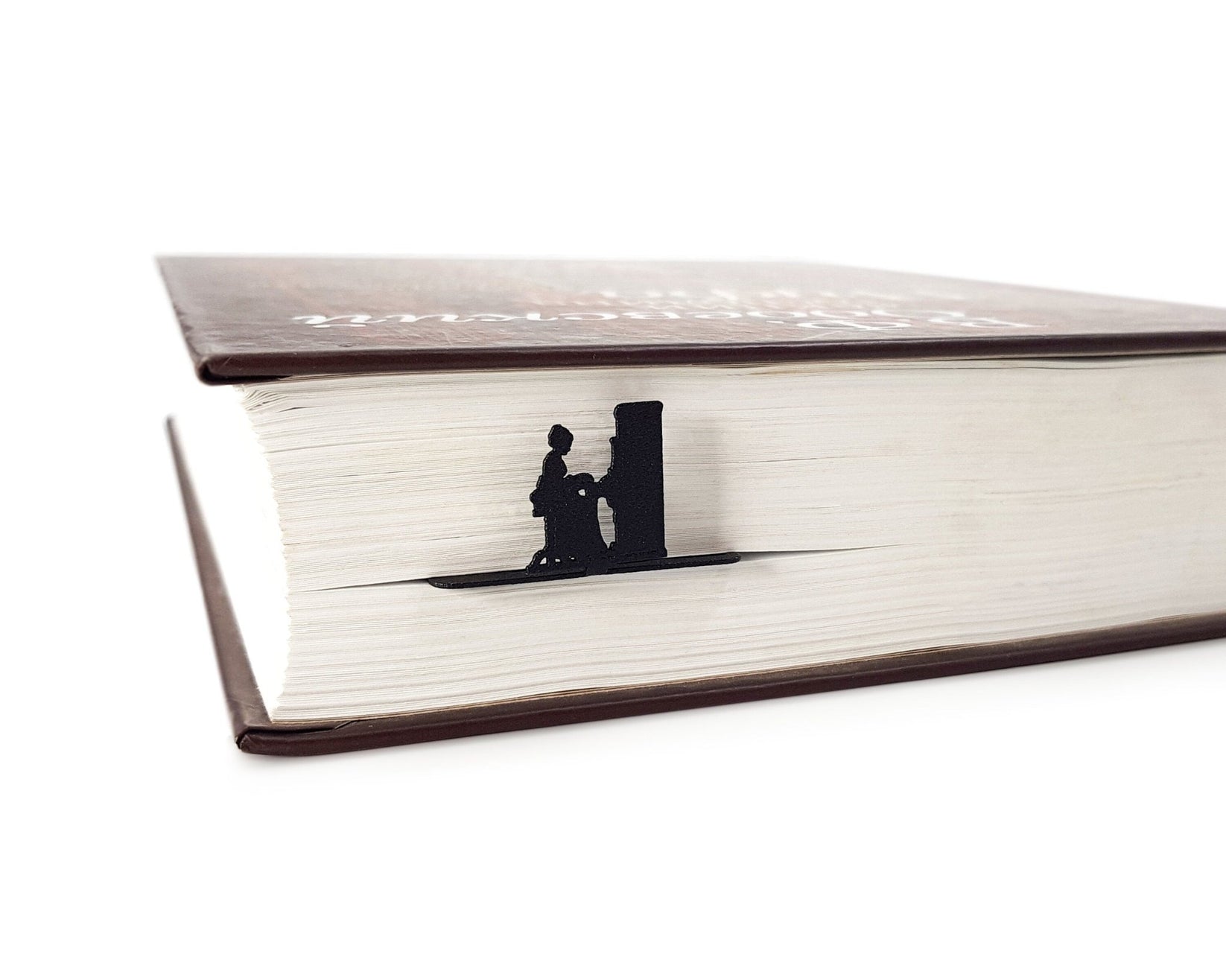 Piano Player metal bookmark in a closed book, only its top showing above the pages