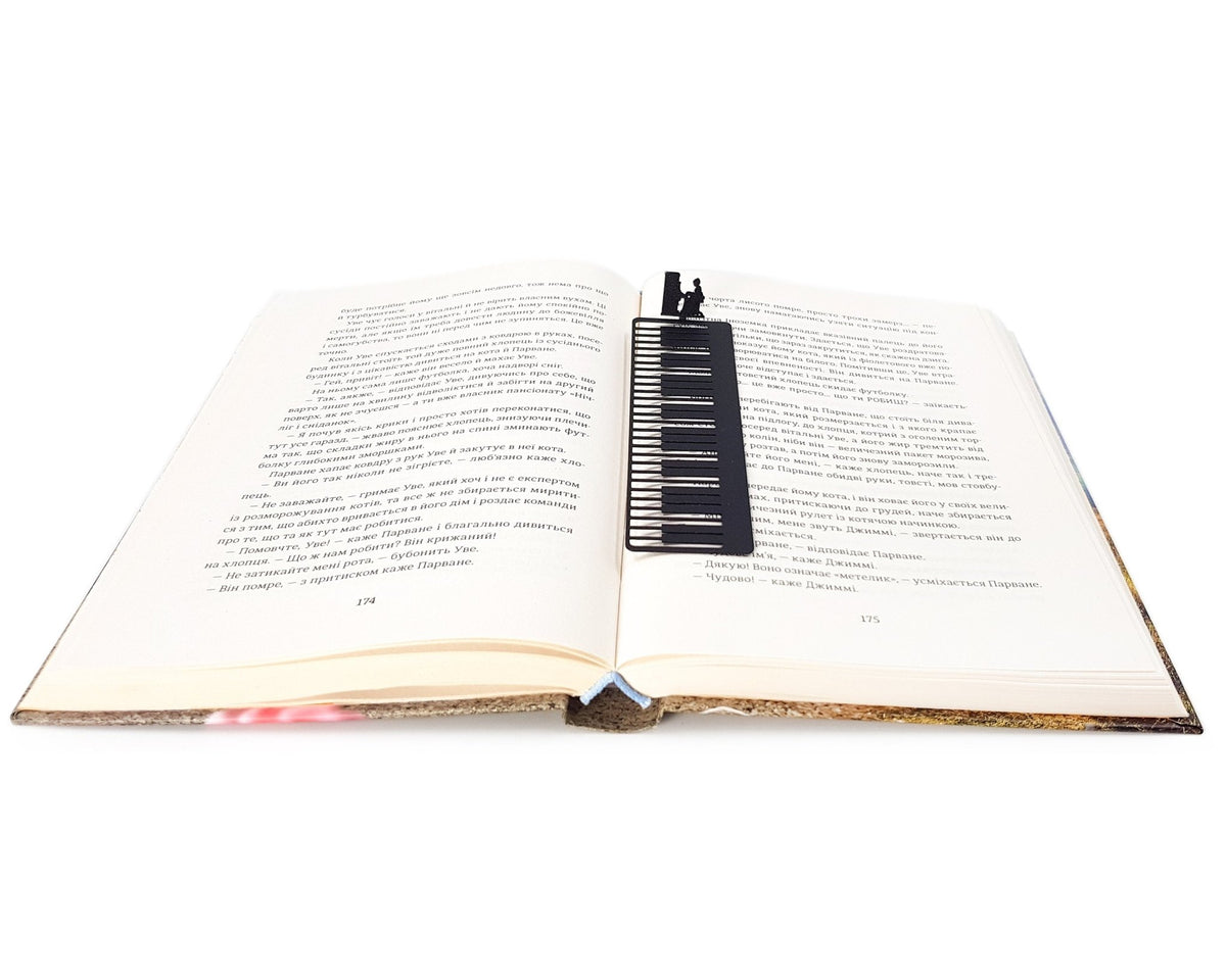 Piano Player metal bookmark lying across the pages of an open book