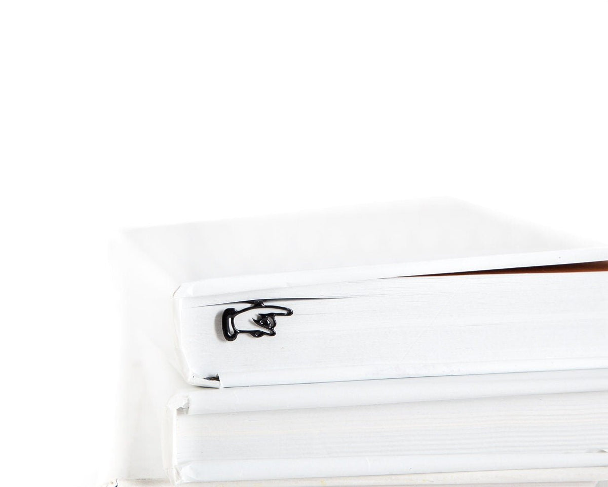 Pointing Finger metal bookmark shown with a stack of books